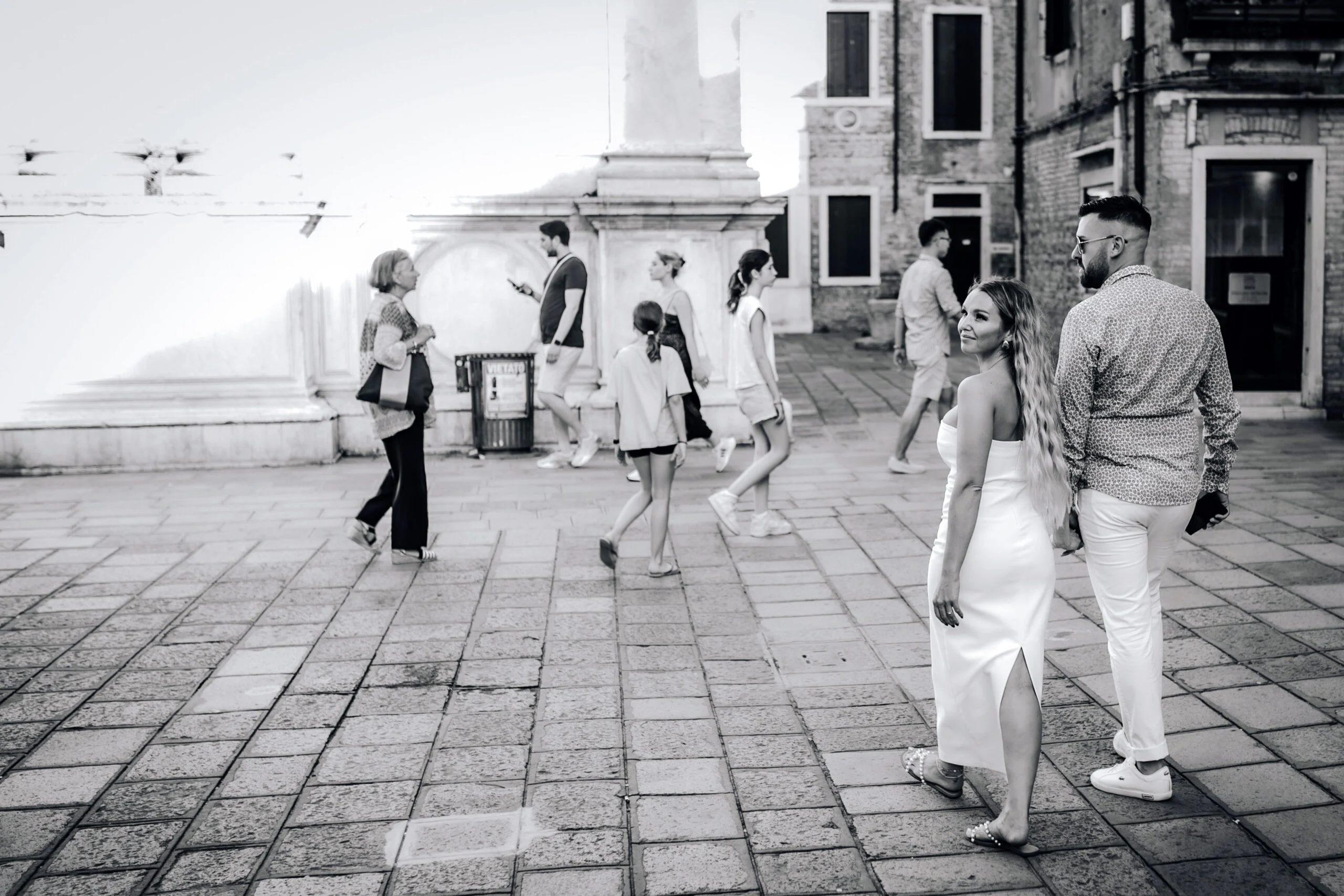 Black and white photograph of the couple crossing a square in Venice