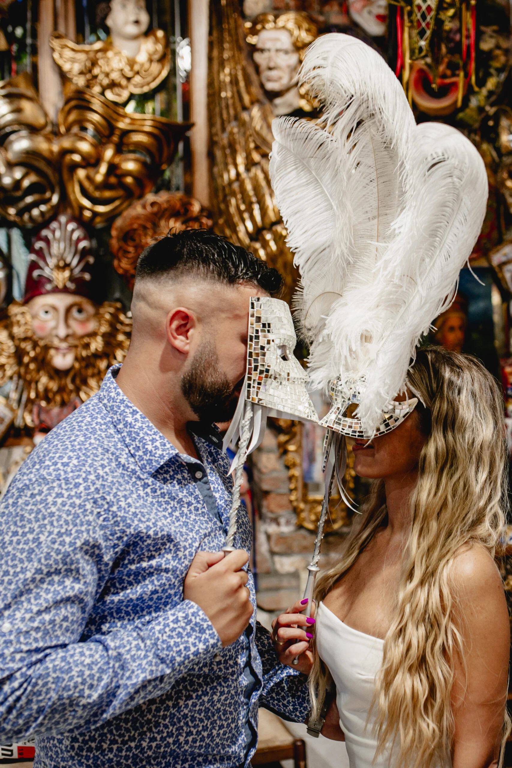 Man holding a white carnival mask up for the woman to see