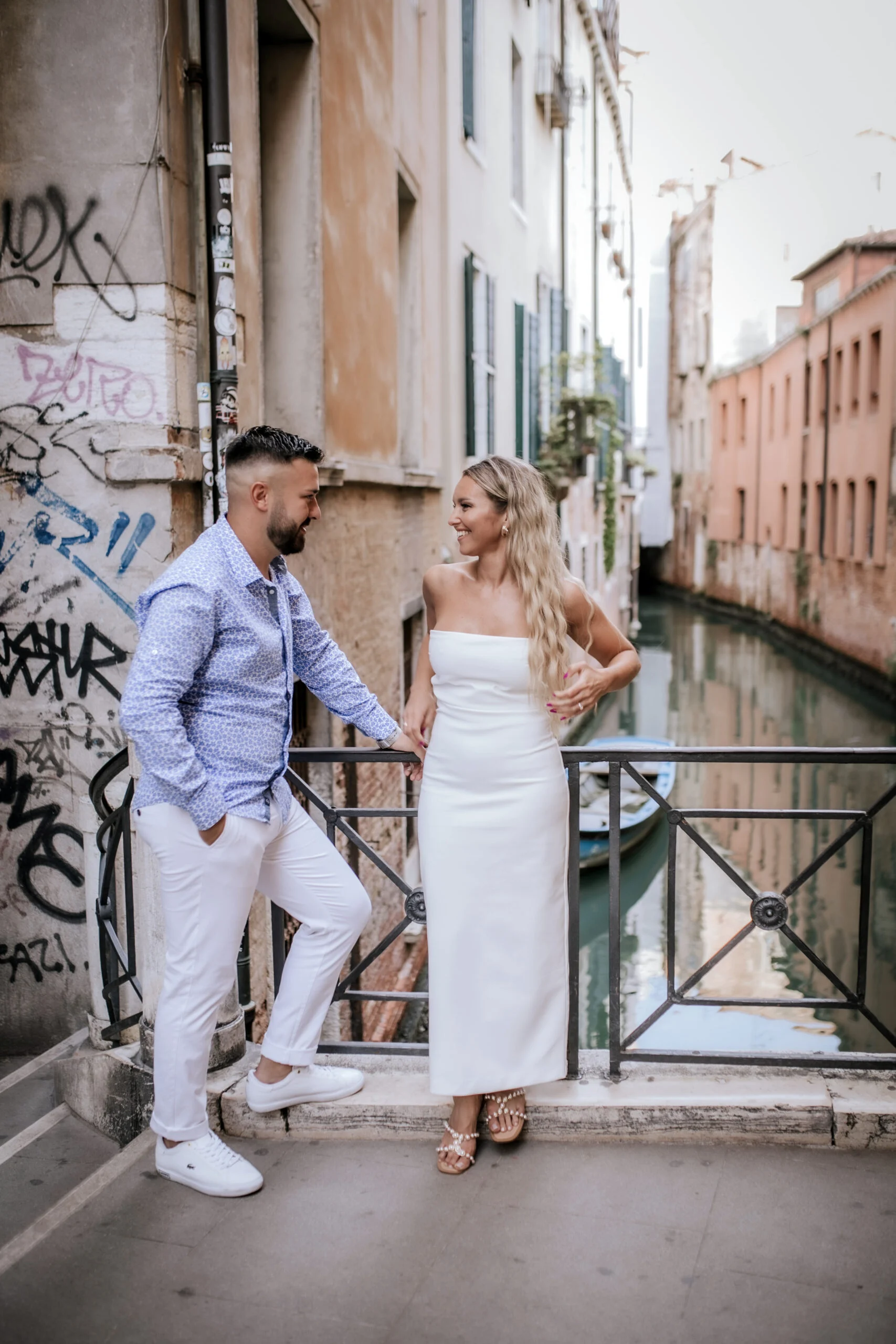 Couple standing by the canal railing in a quiet alley
