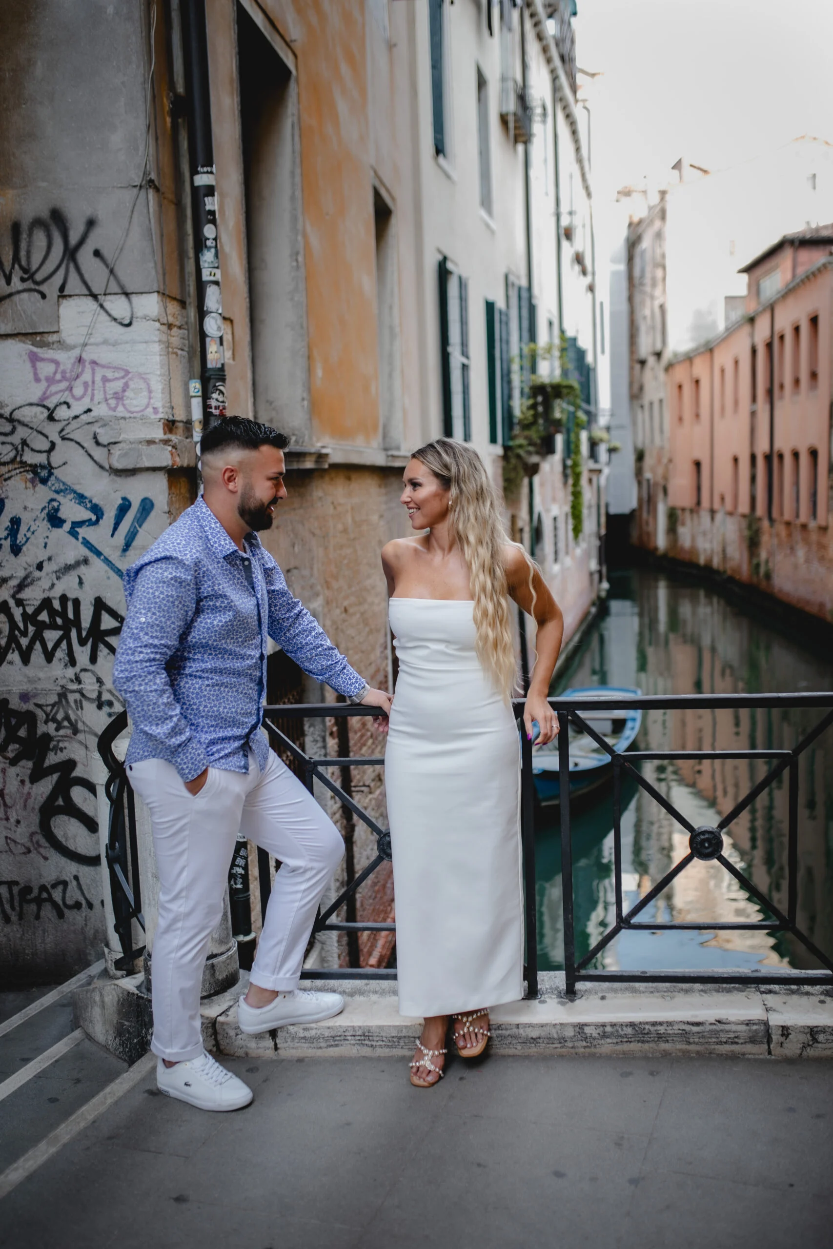 Couple leaning on a railing above a small canal
