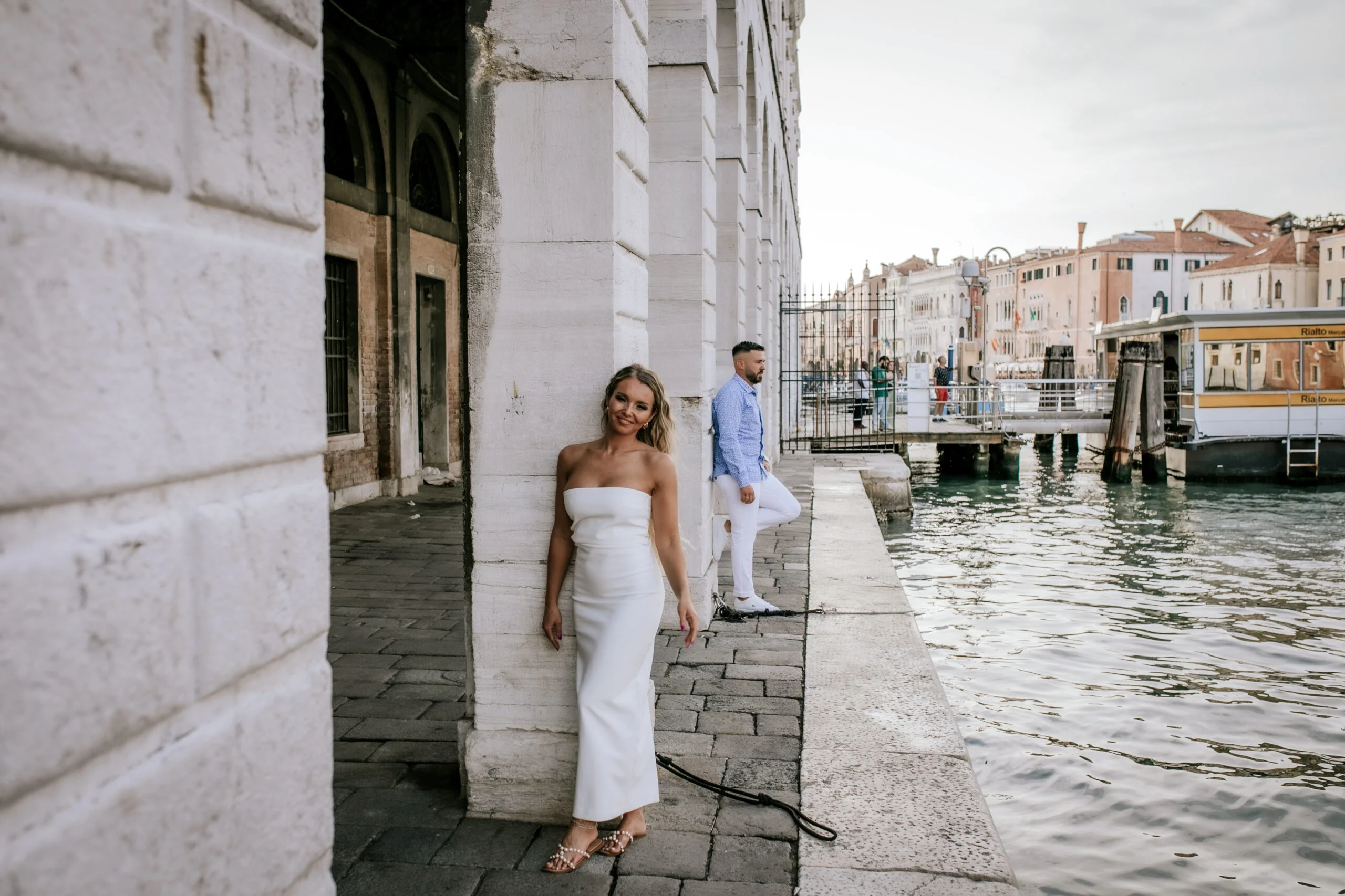 Woman standing against a stone wall by the water
