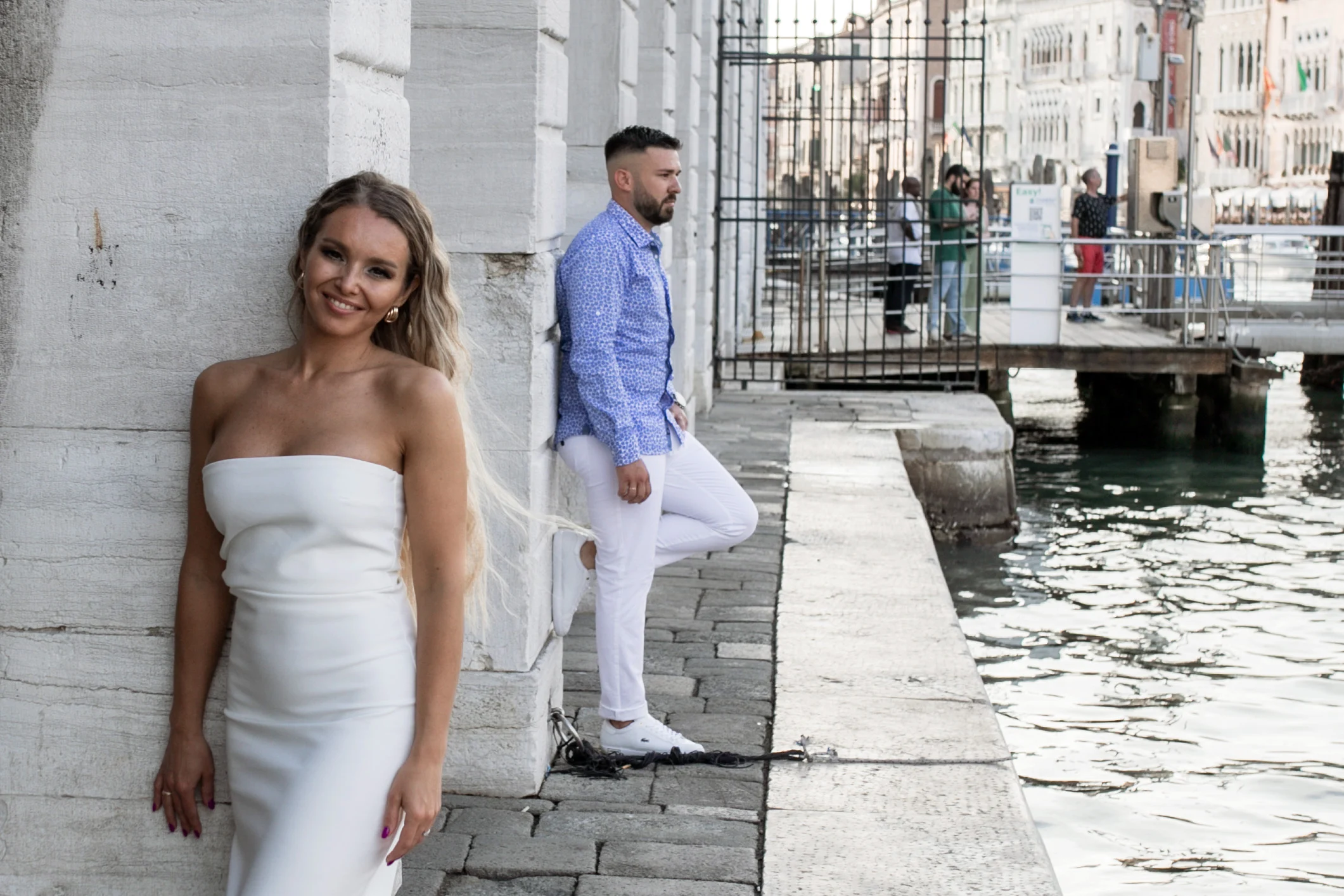 Woman smiling at the camera, the man behind her on the quay
