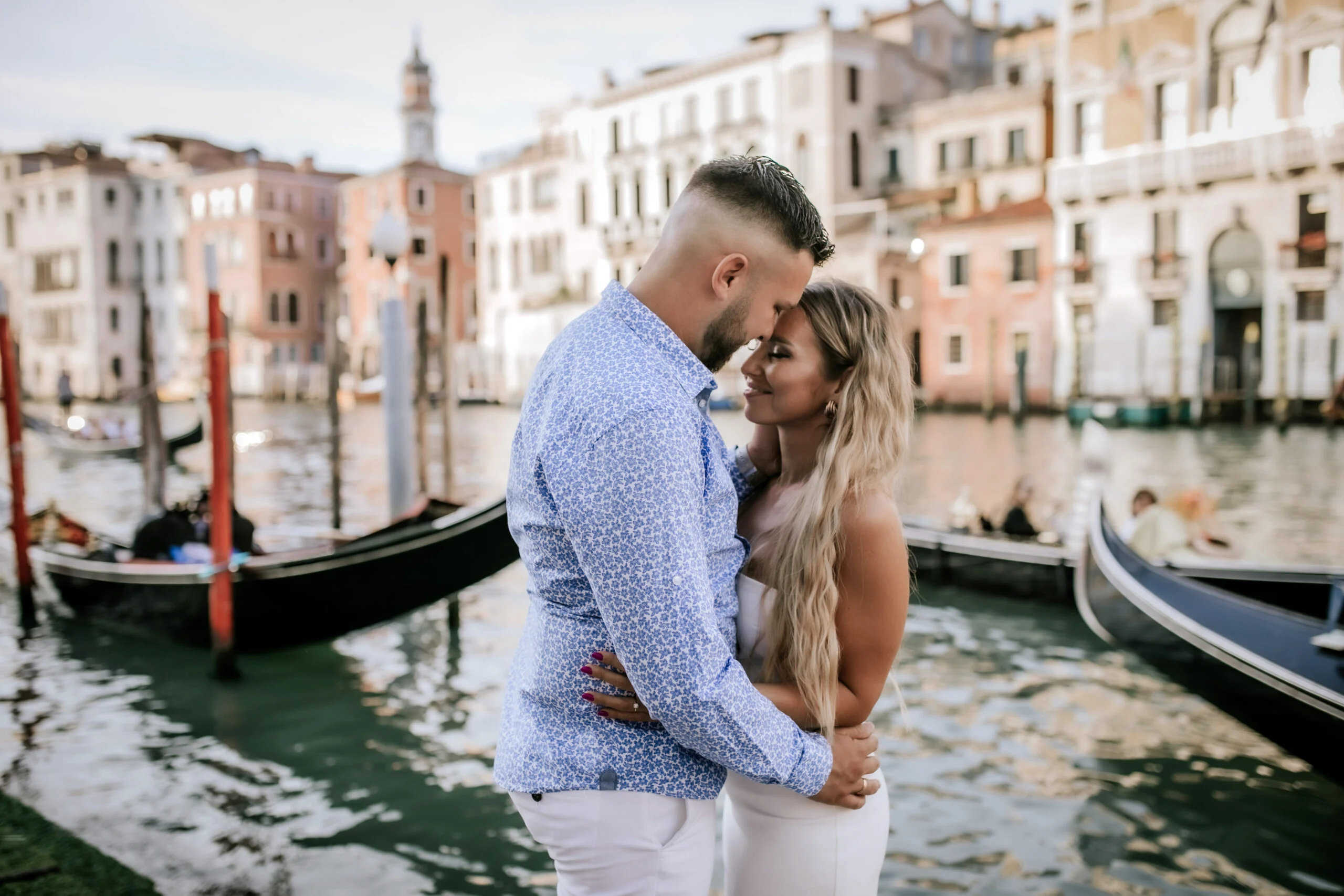 Couple embracing with gondolas moored behind them