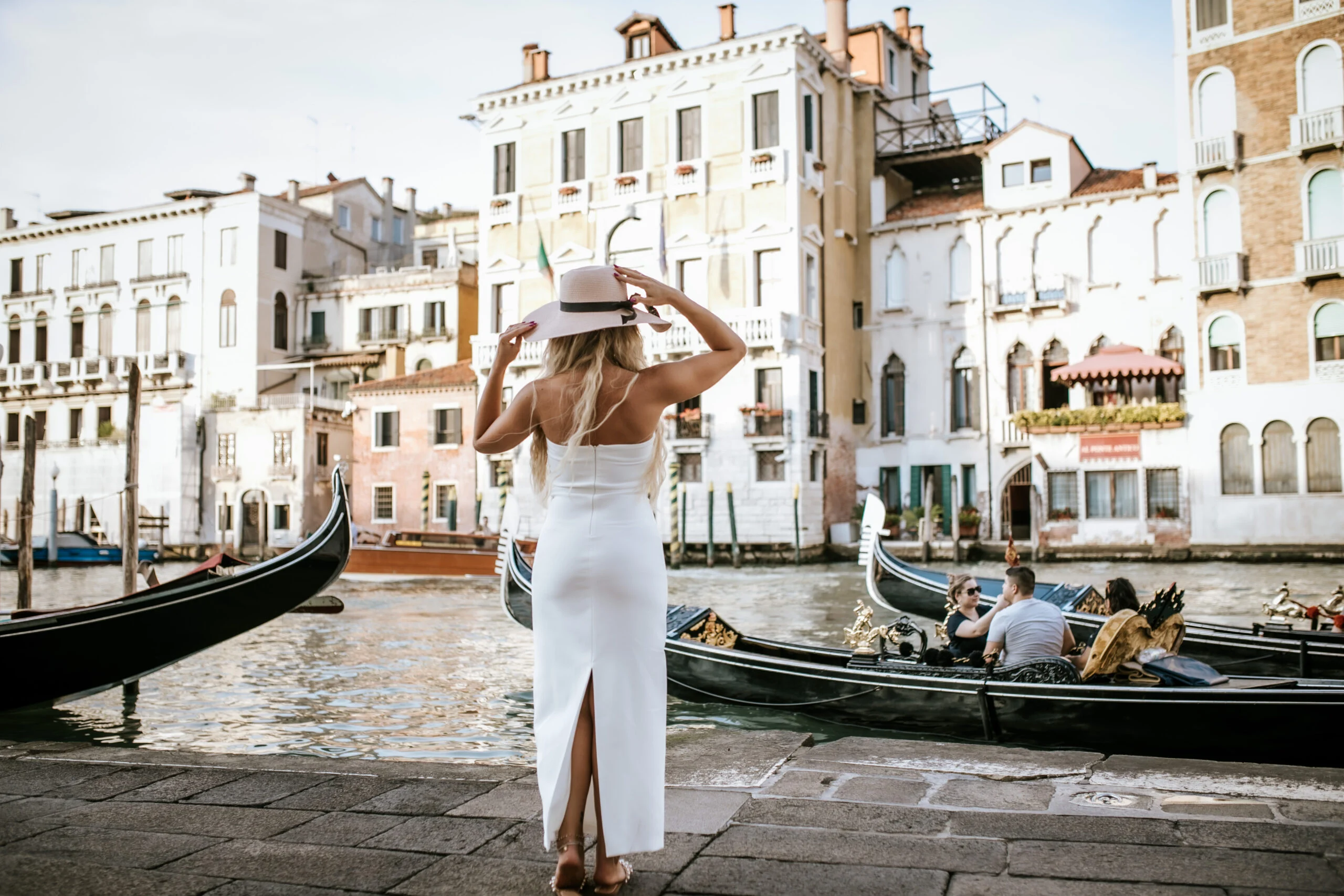 Woman adjusting her hat with the canal behind her