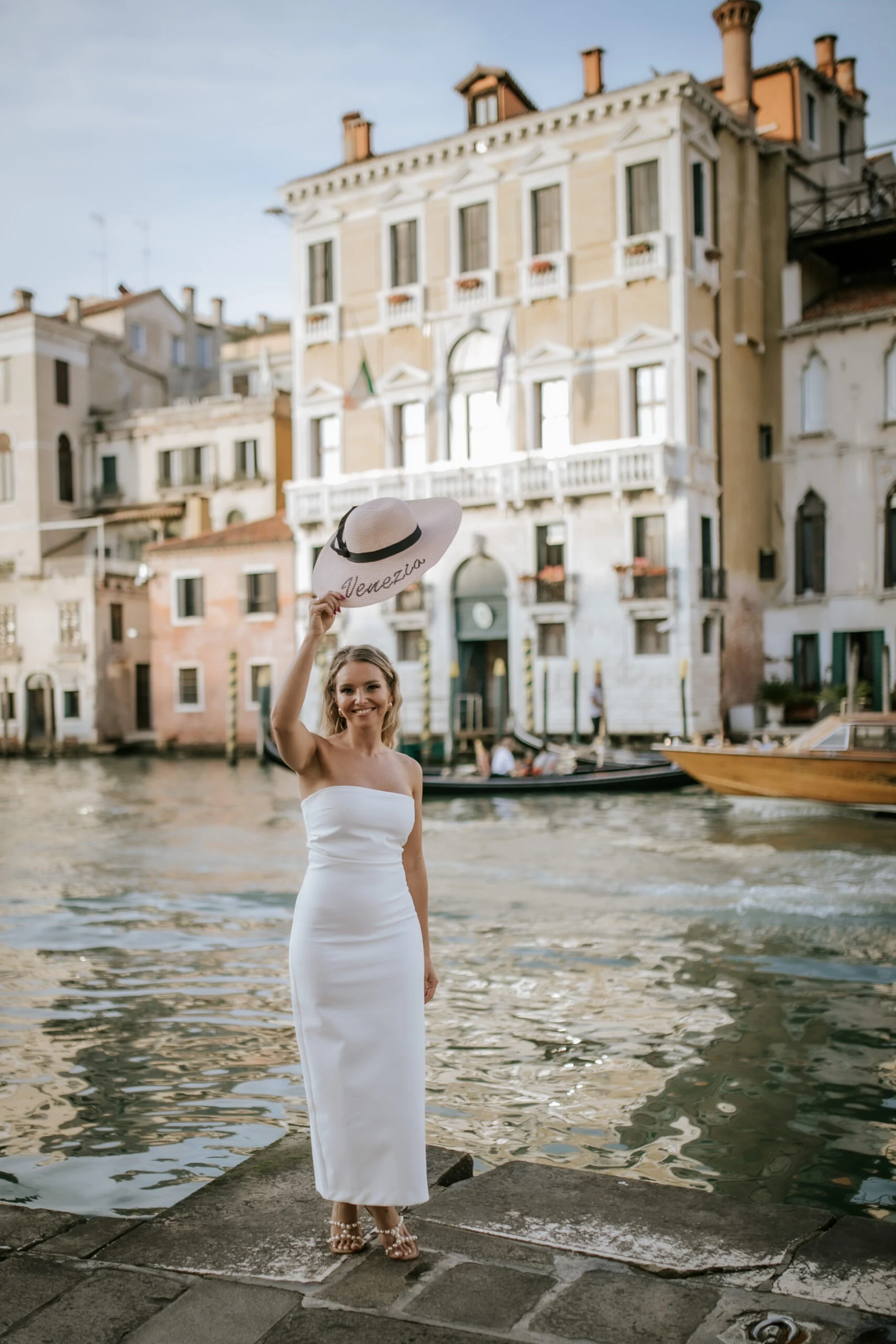 Woman holding up her hat on the quay