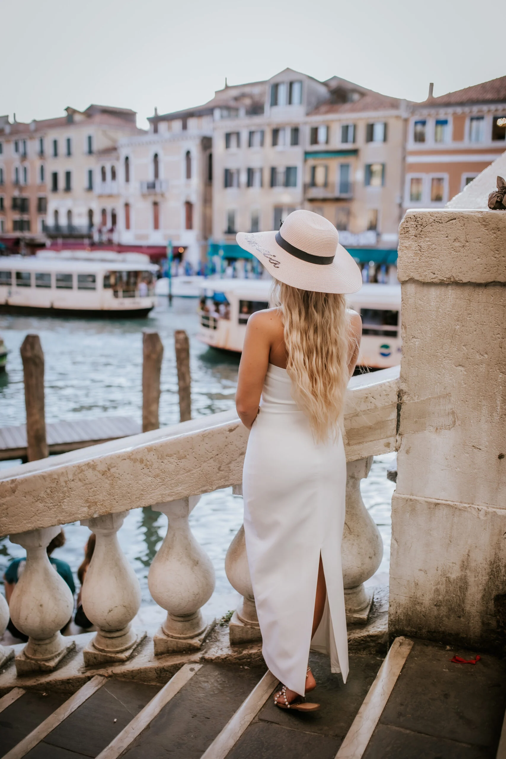 Woman in a straw hat looking out over the canal from a bridge