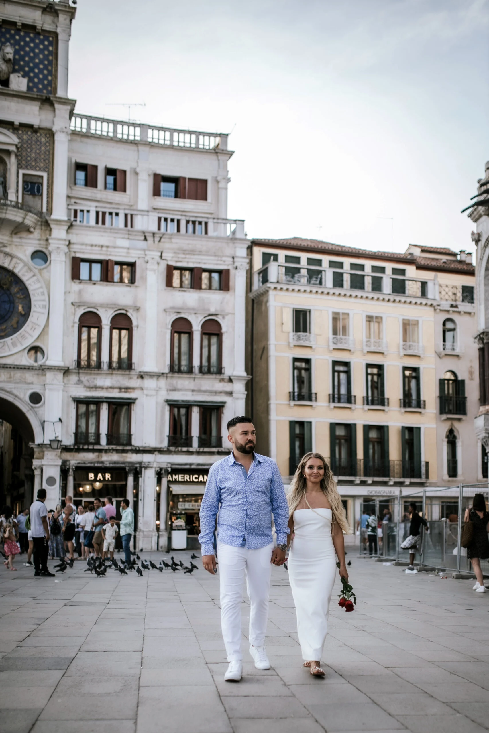Couple crossing the square, the woman carrying roses