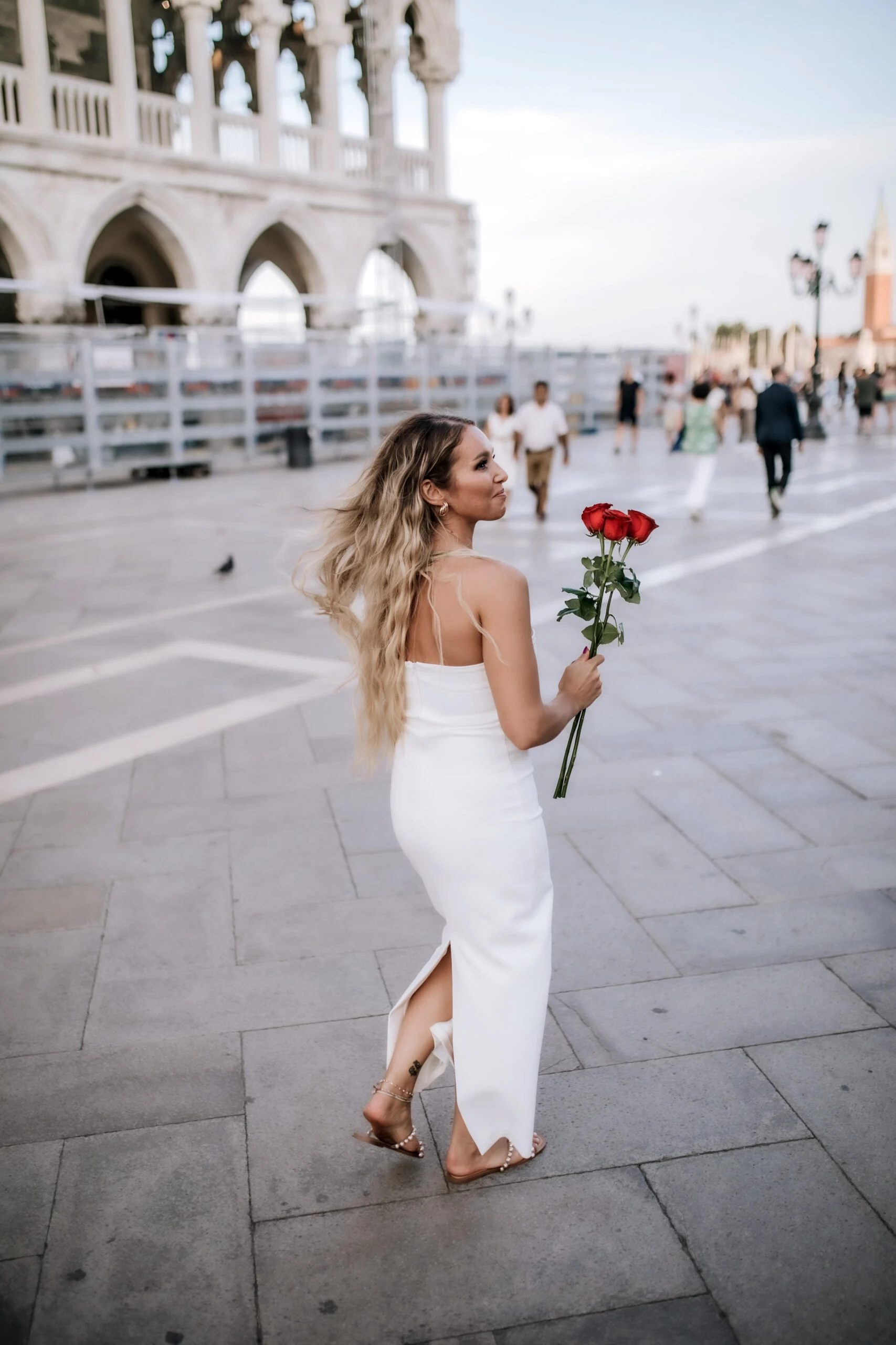 Woman walking across the square carrying roses