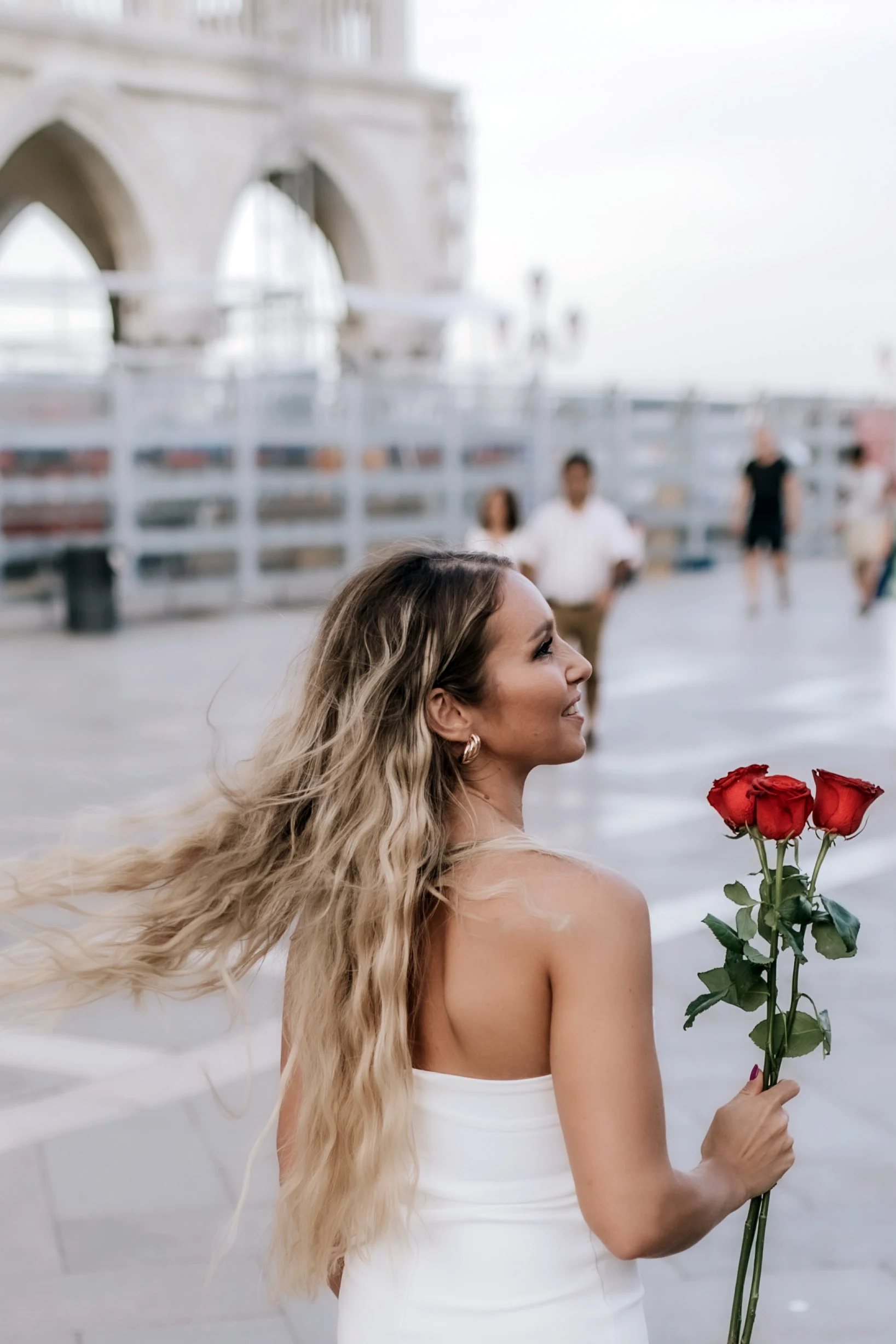 Woman turning with roses in her hand, her hair caught by the wind