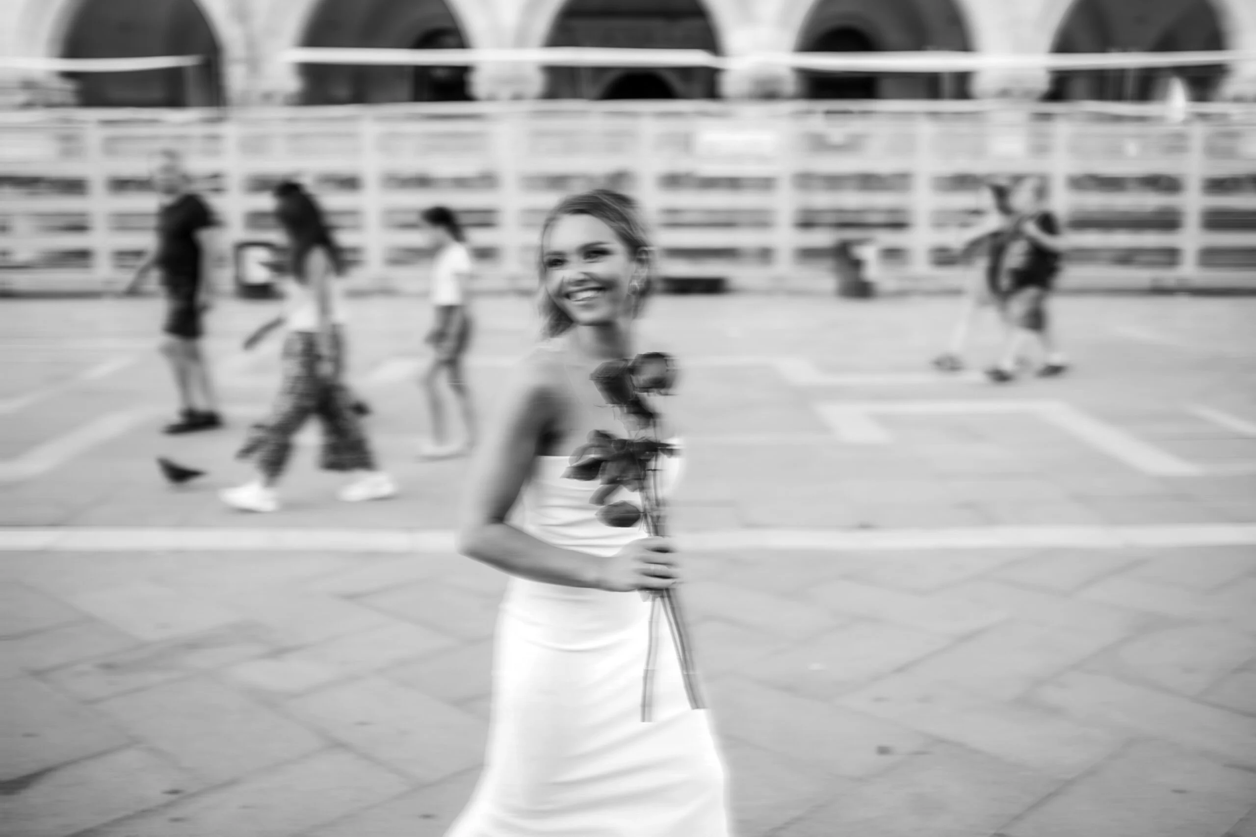 Black and white photograph of the woman in the square as people pass