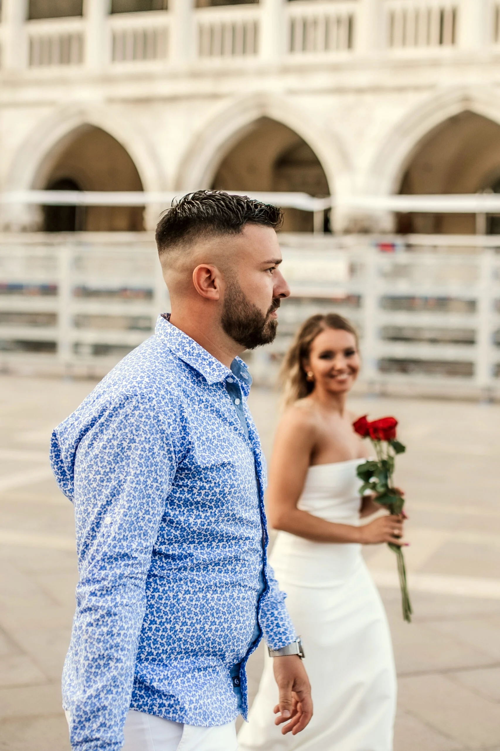 Couple walking under the arcade, the woman holding red roses