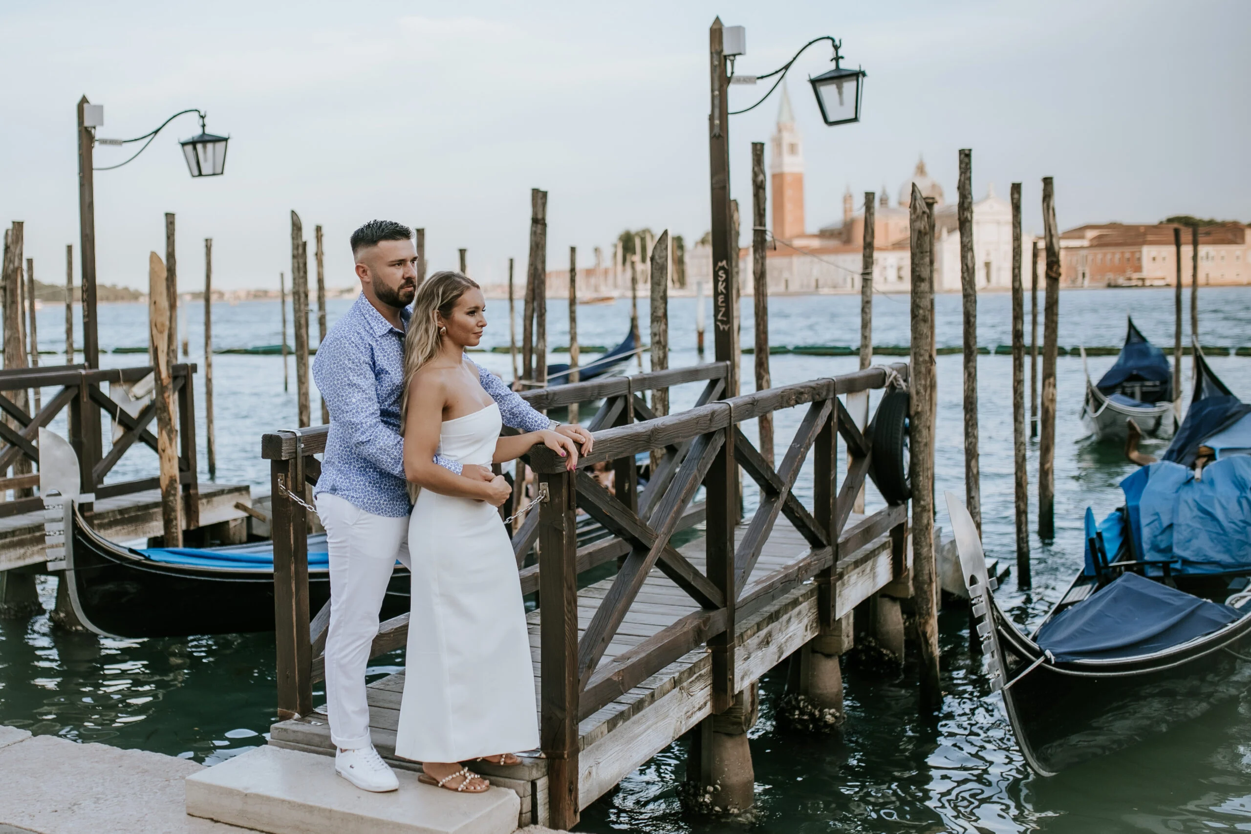 Couple leaning on the railing above the gondolas