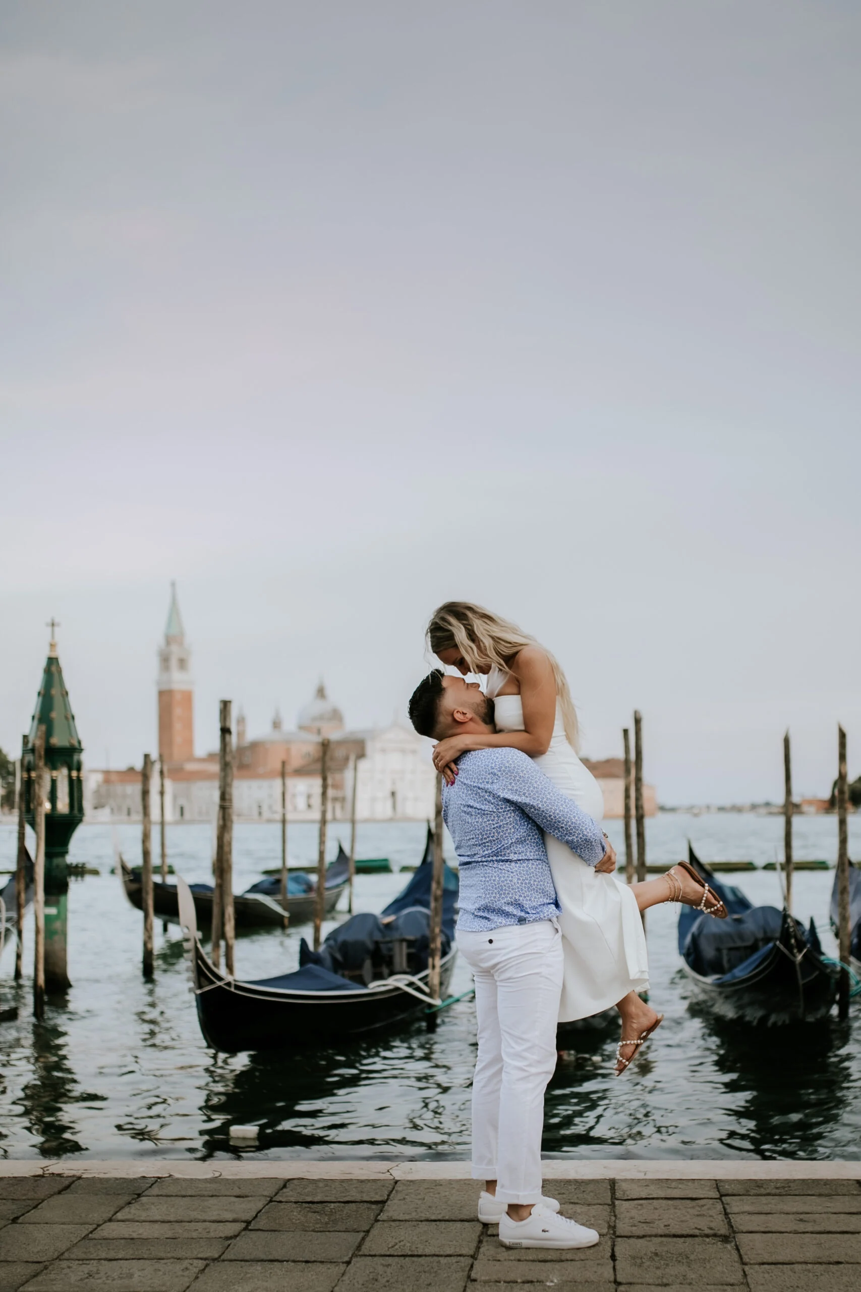 Man lifting the woman on the Venetian waterfront