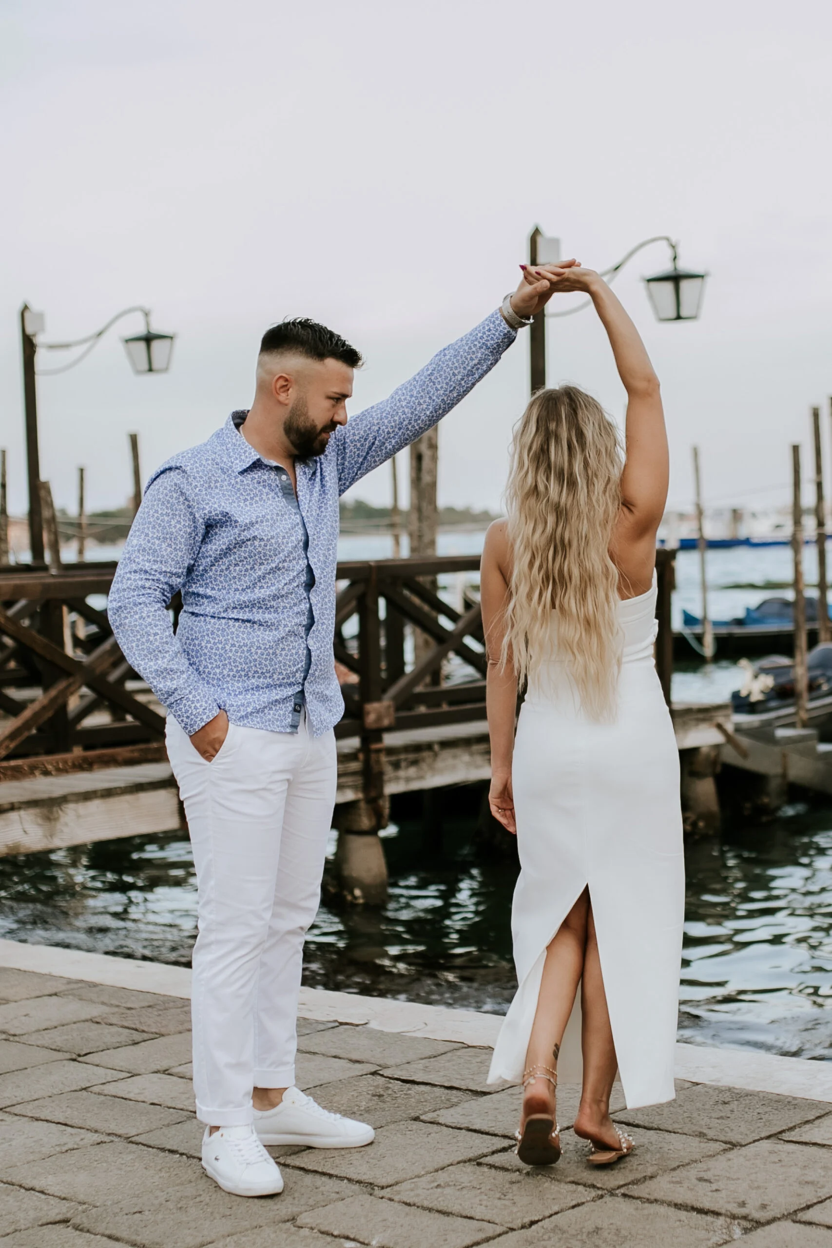 Man turning the woman under his arm beside the gondolas
