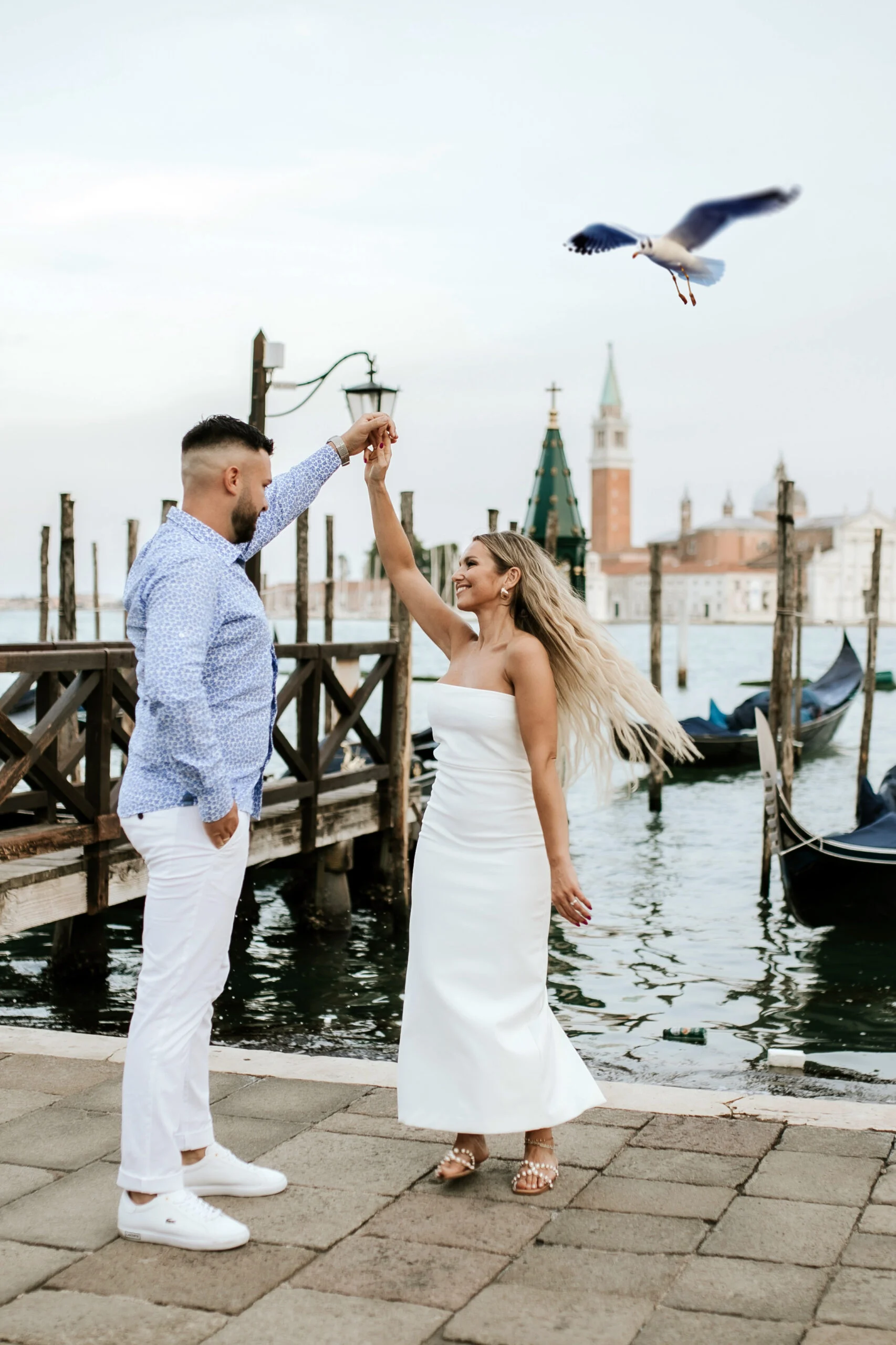 Couple dancing on the waterfront as a seagull passes overhead