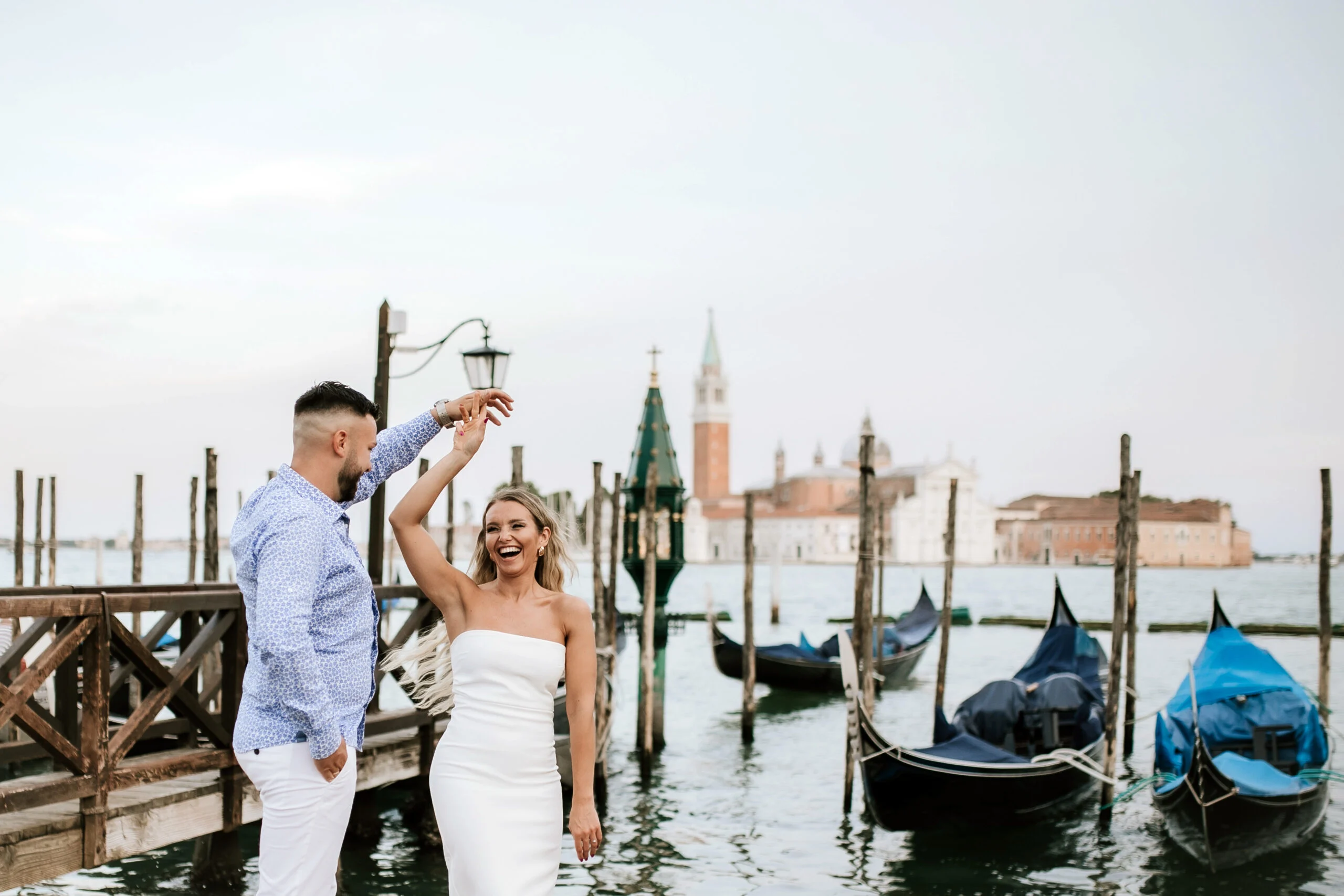 Man spinning the woman beside the moored gondolas