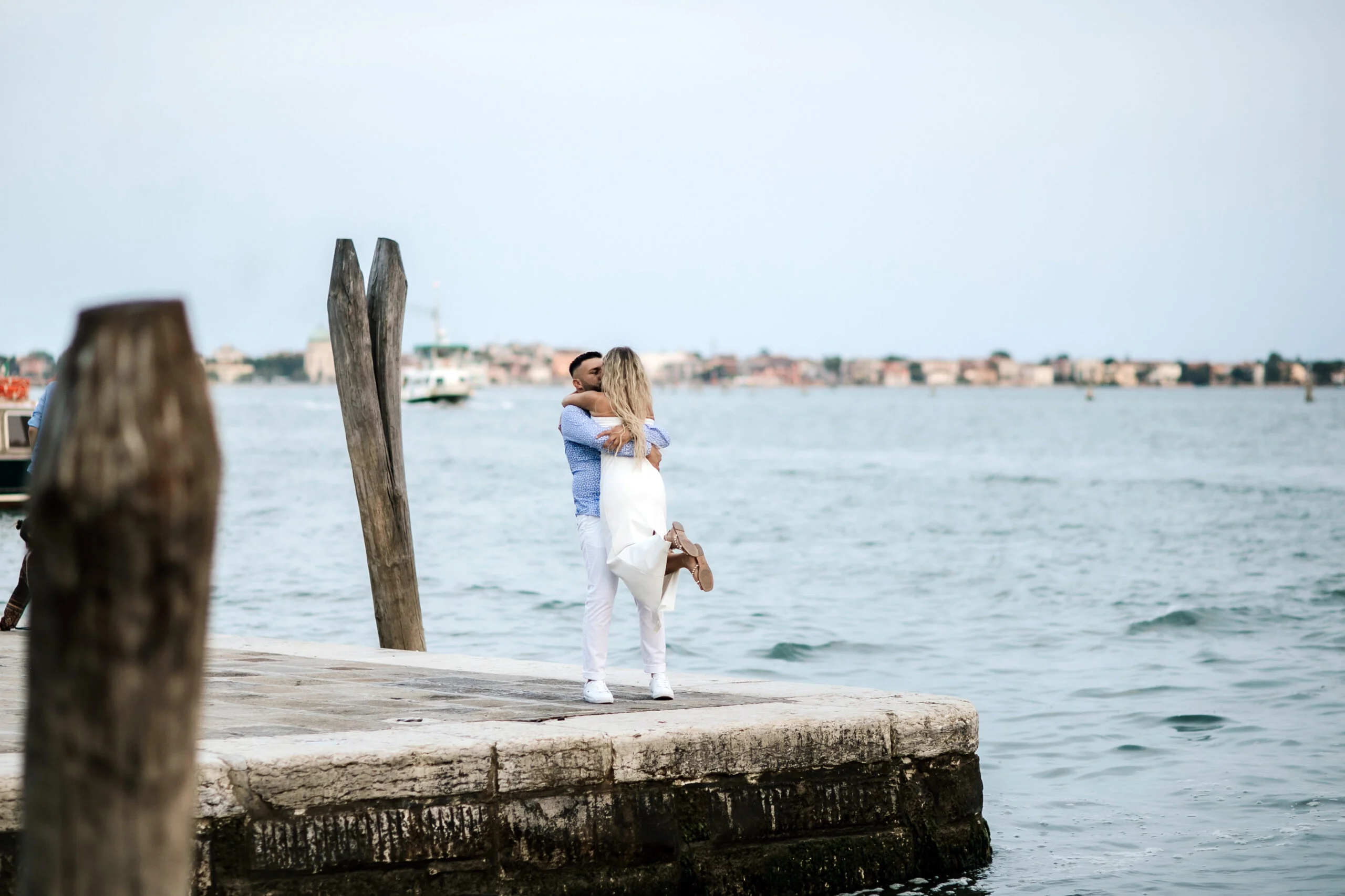 Couple on the waterfront beside the wooden mooring poles