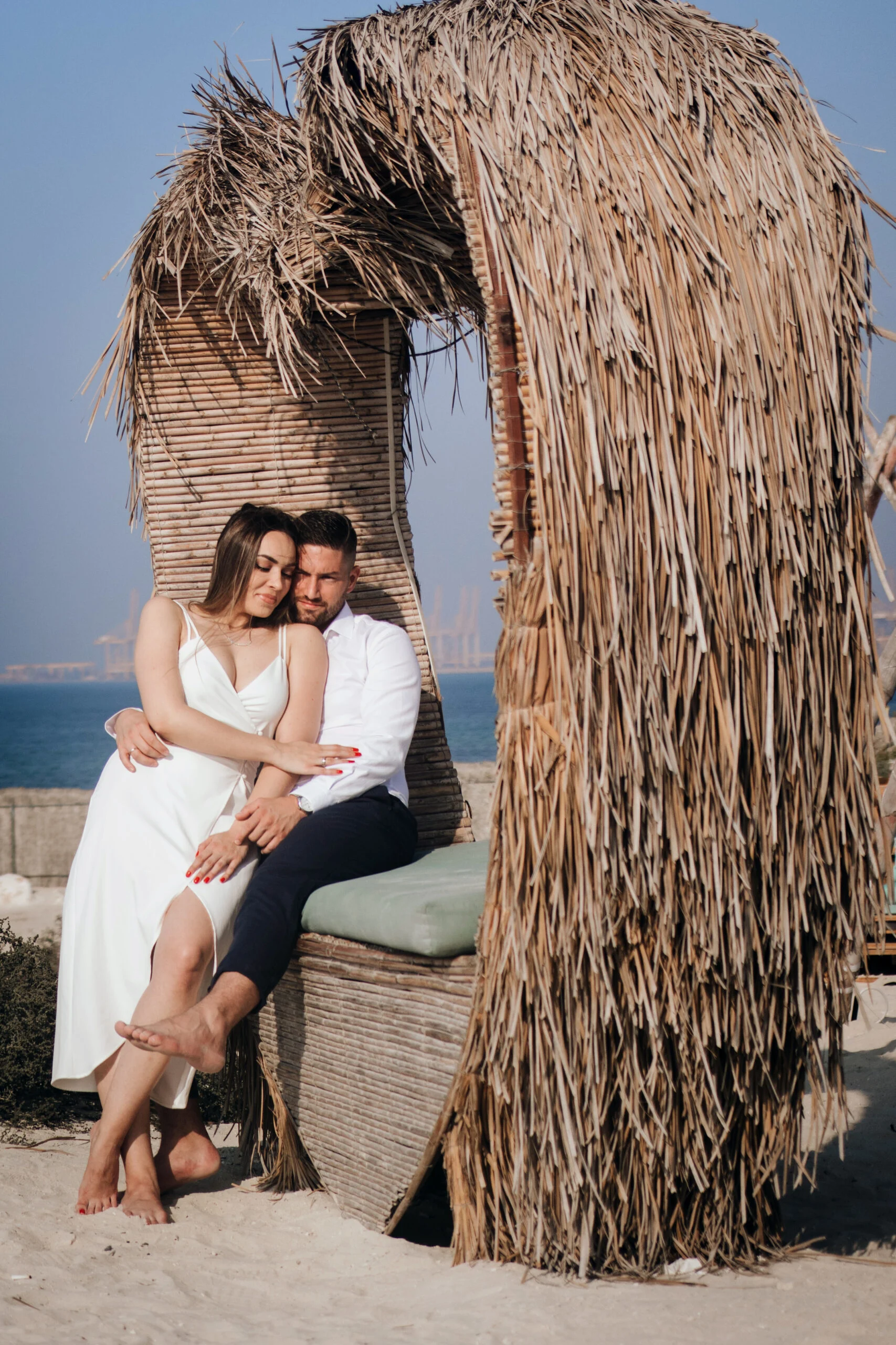 Couple sitting under a palm-thatched shelter on the sand