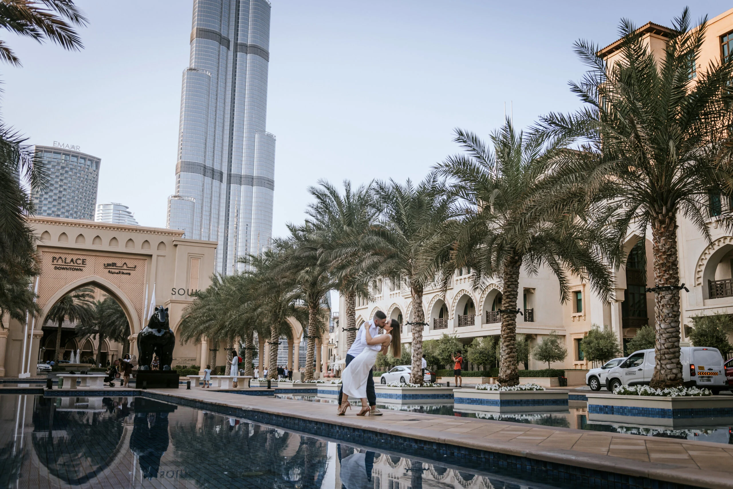 Woman walking beside a long reflecting pool with the Burj Khalifa behind her