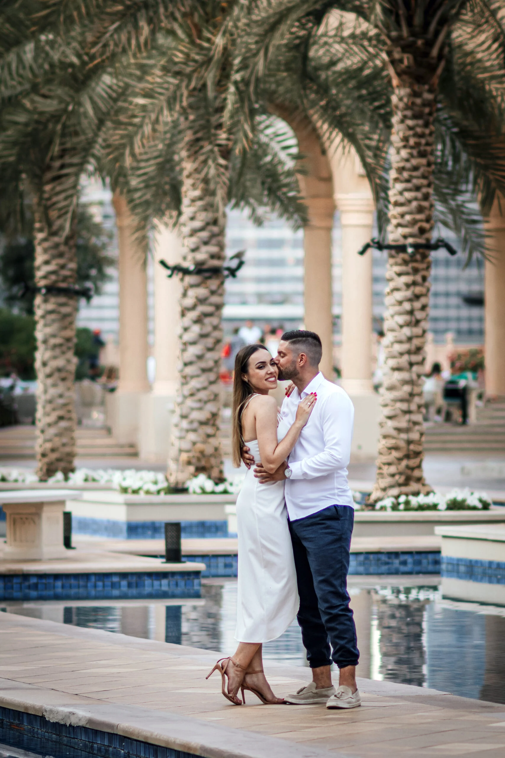Couple embracing between palm trees beside the water