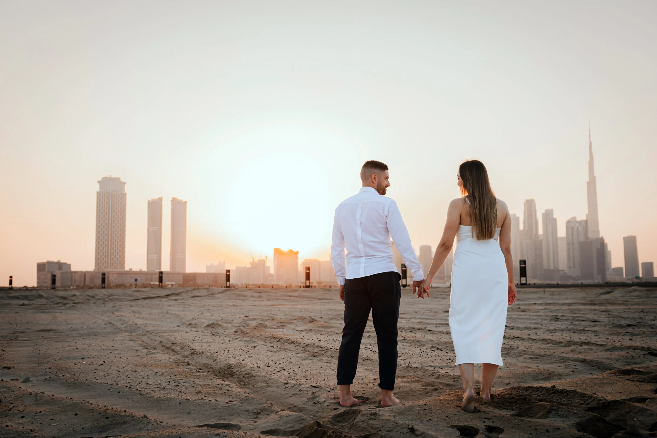 Couple walking along the shore towards the skyline at sunset