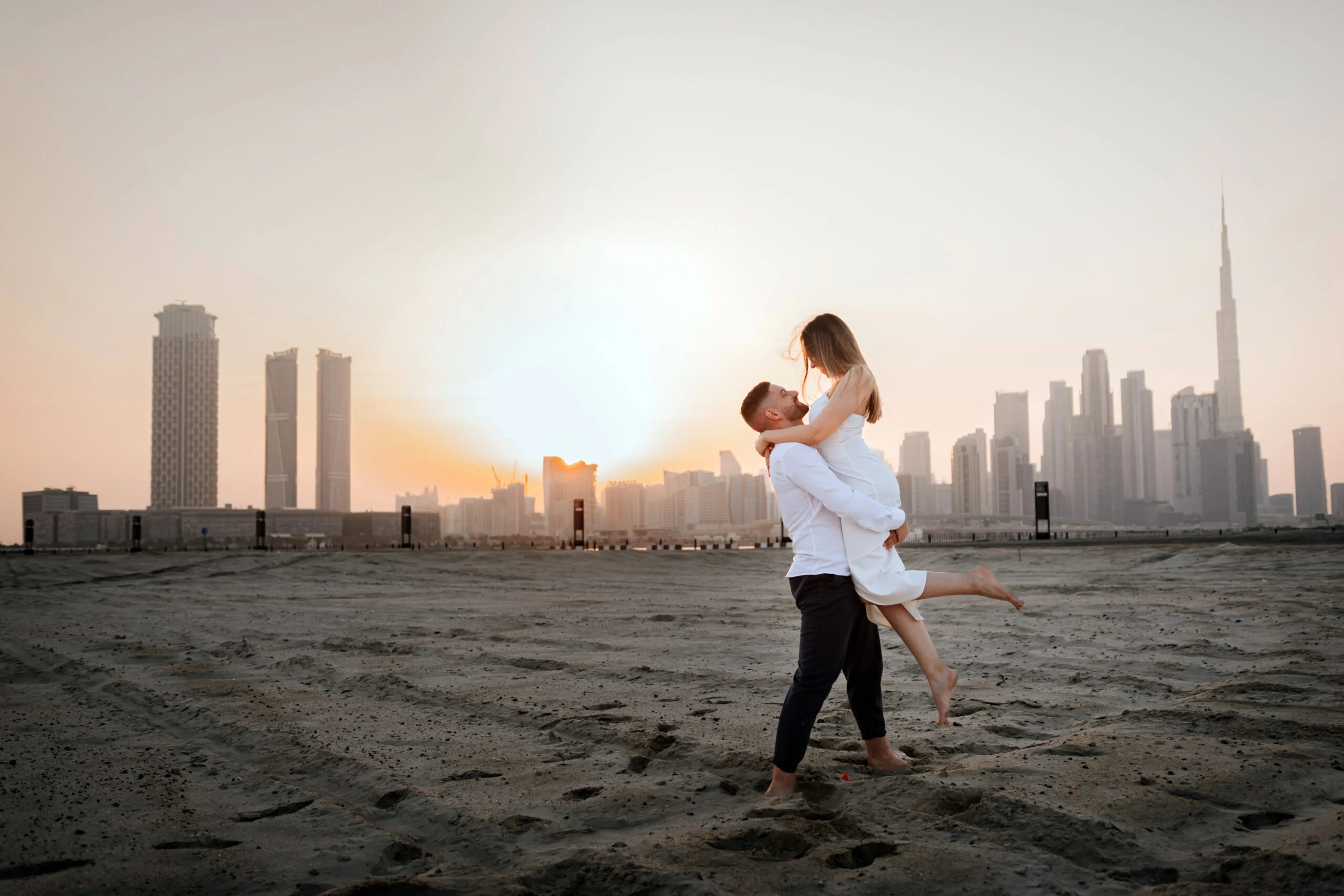 Man lifting the woman on the beach at sunset