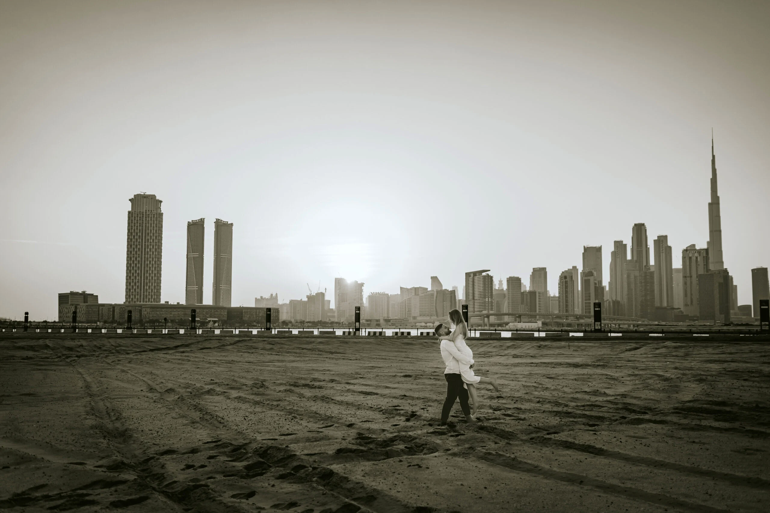 Couple standing on the empty beach with the skyline behind them