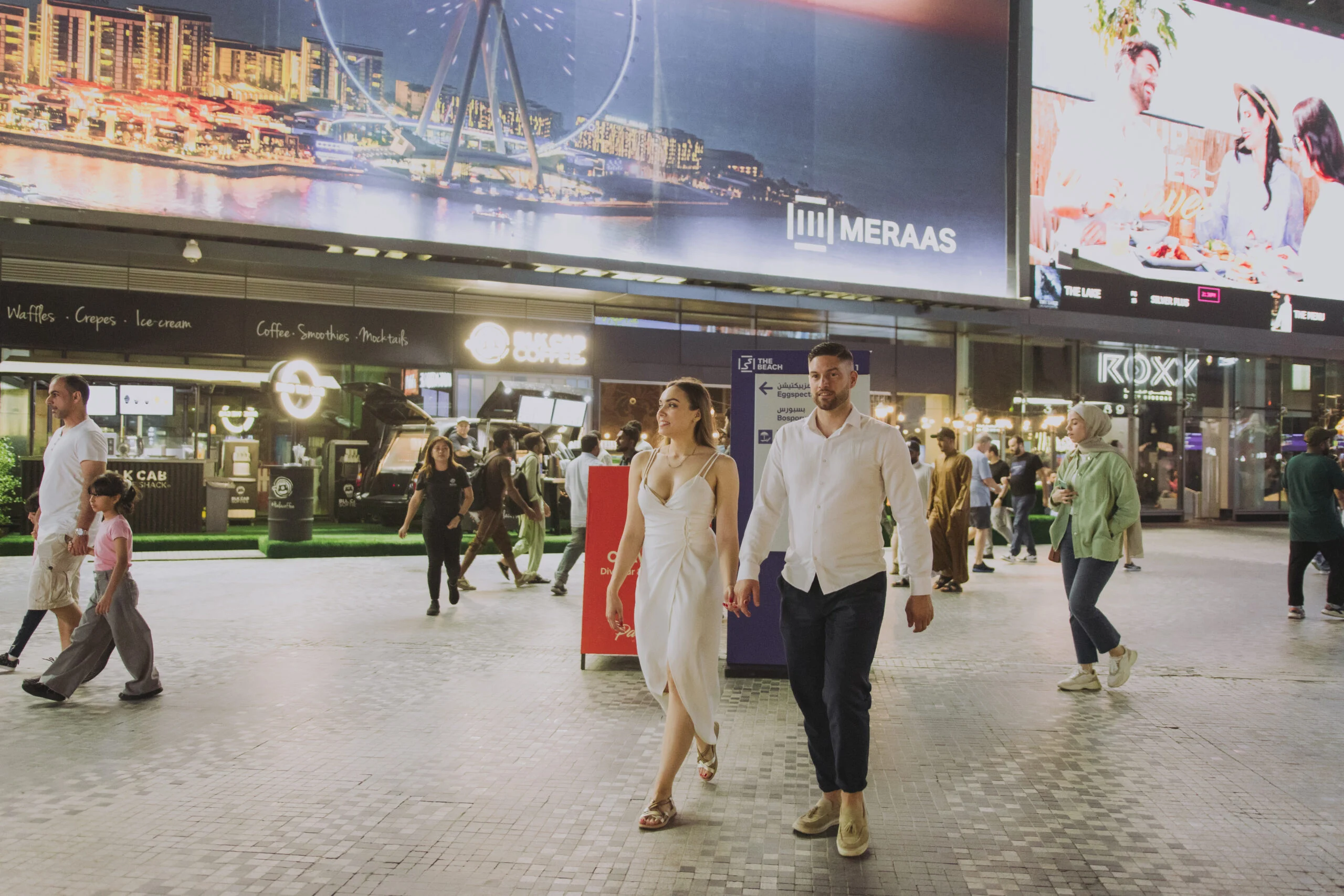 Couple walking past lit hoardings at night
