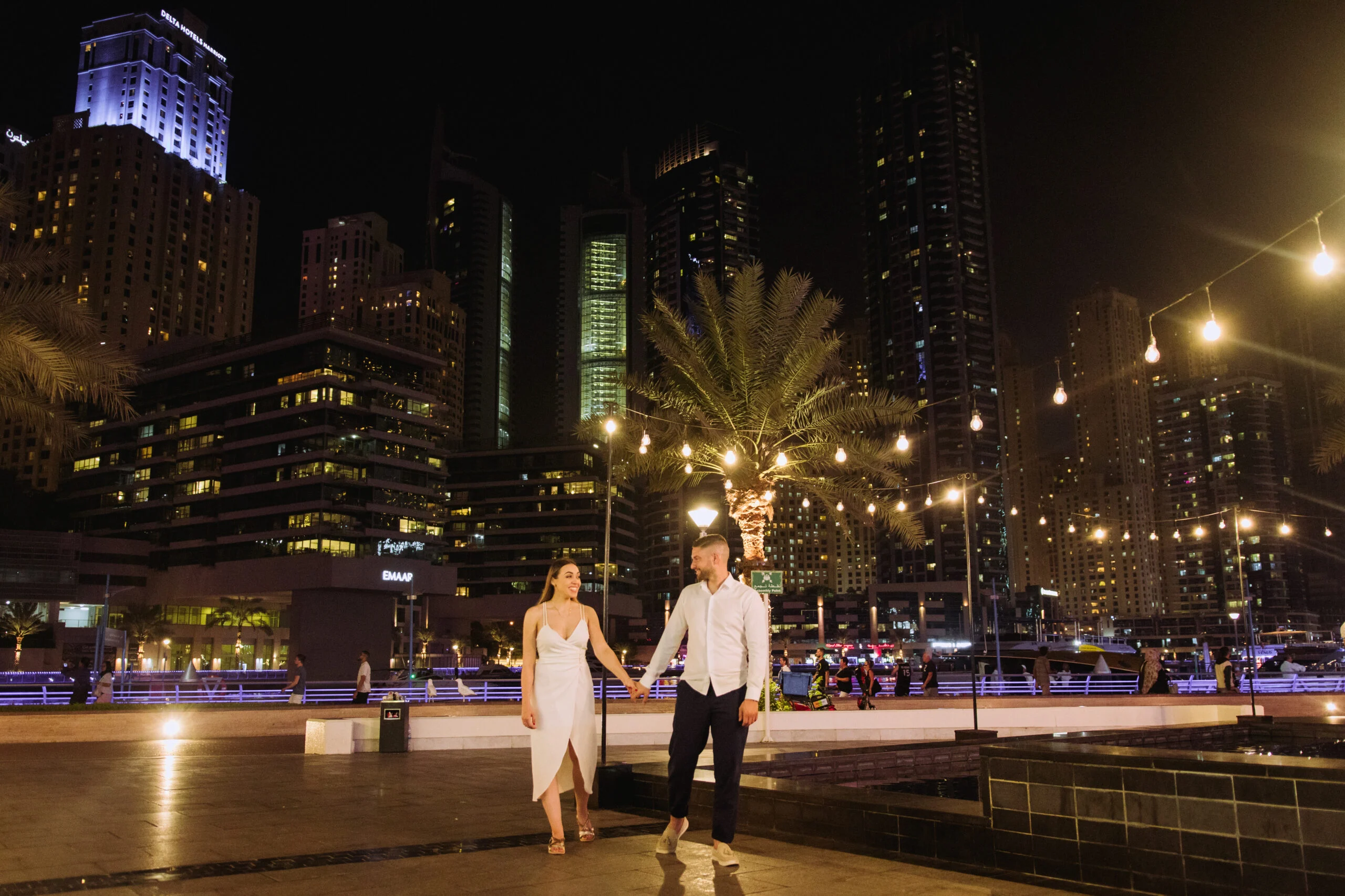 Couple walking hand in hand along the marina at night