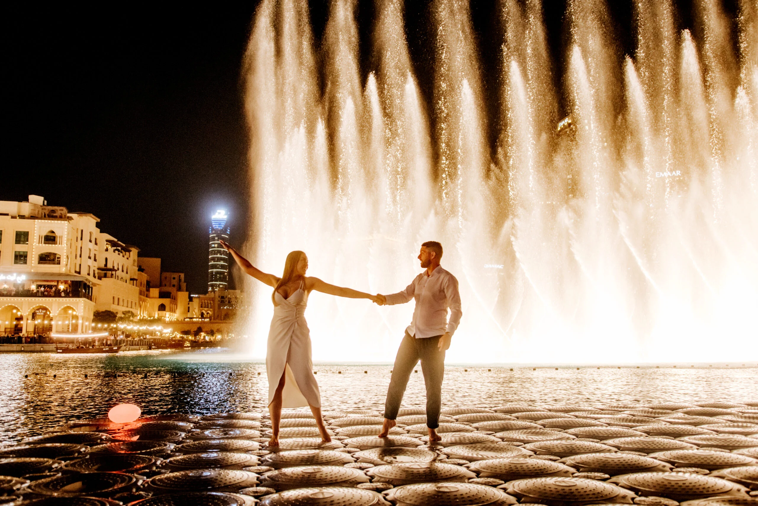 Couple standing hand in hand as the fountains rise behind them
