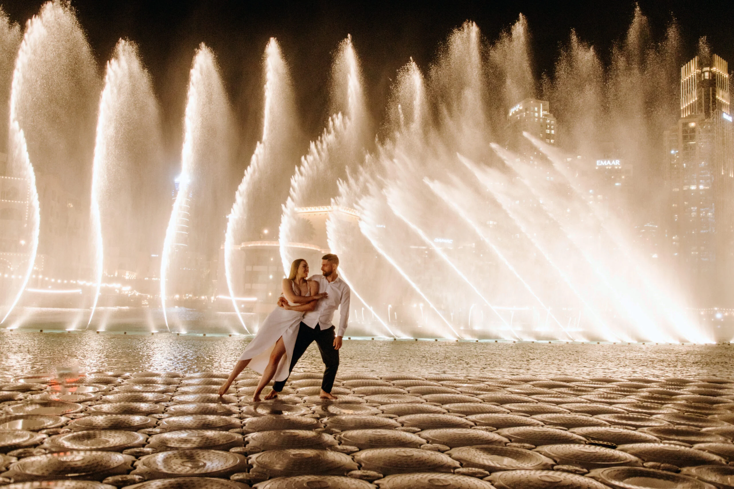 Couple by the fountain pool, the water lit from below