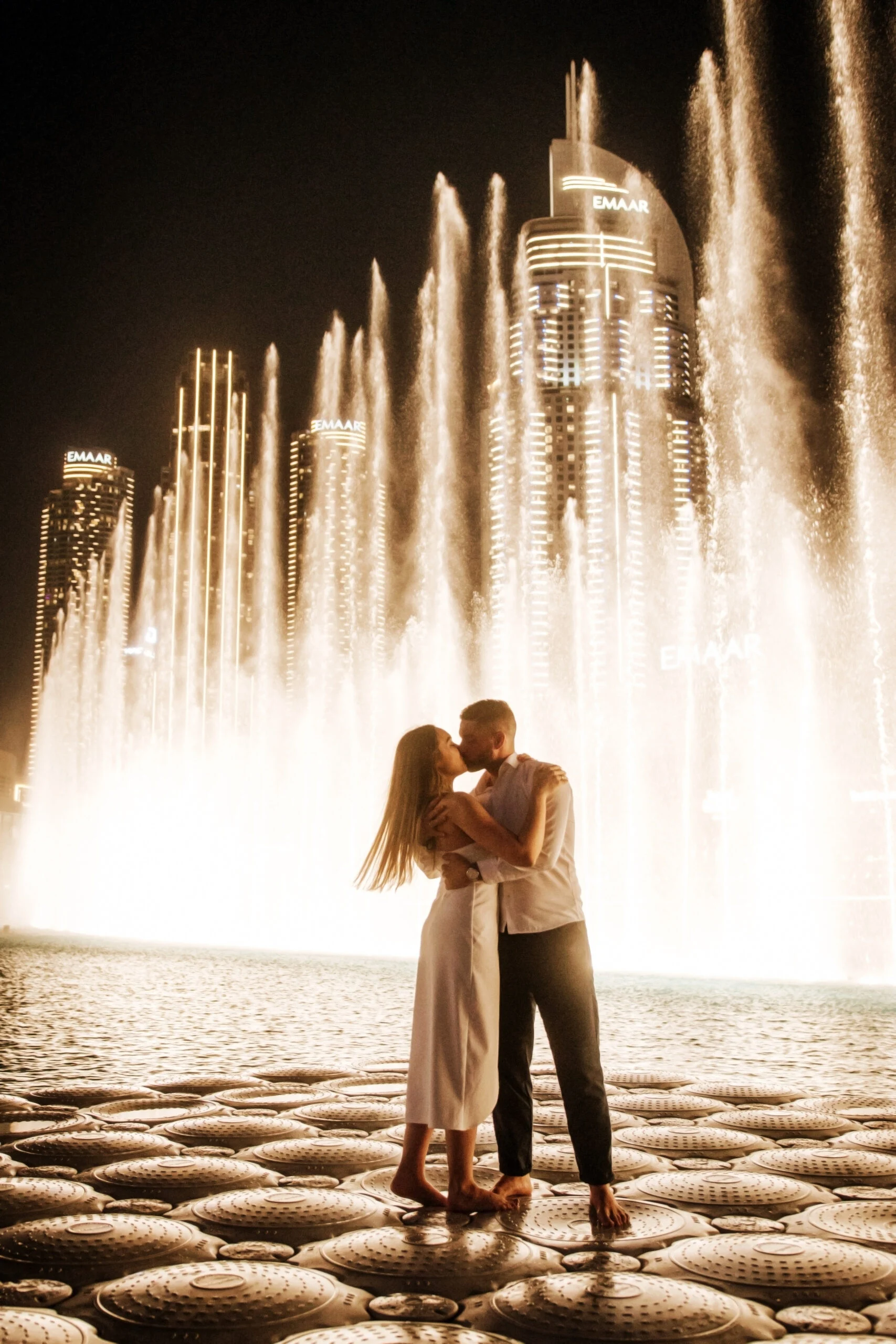 Couple embracing as the fountains rise behind them