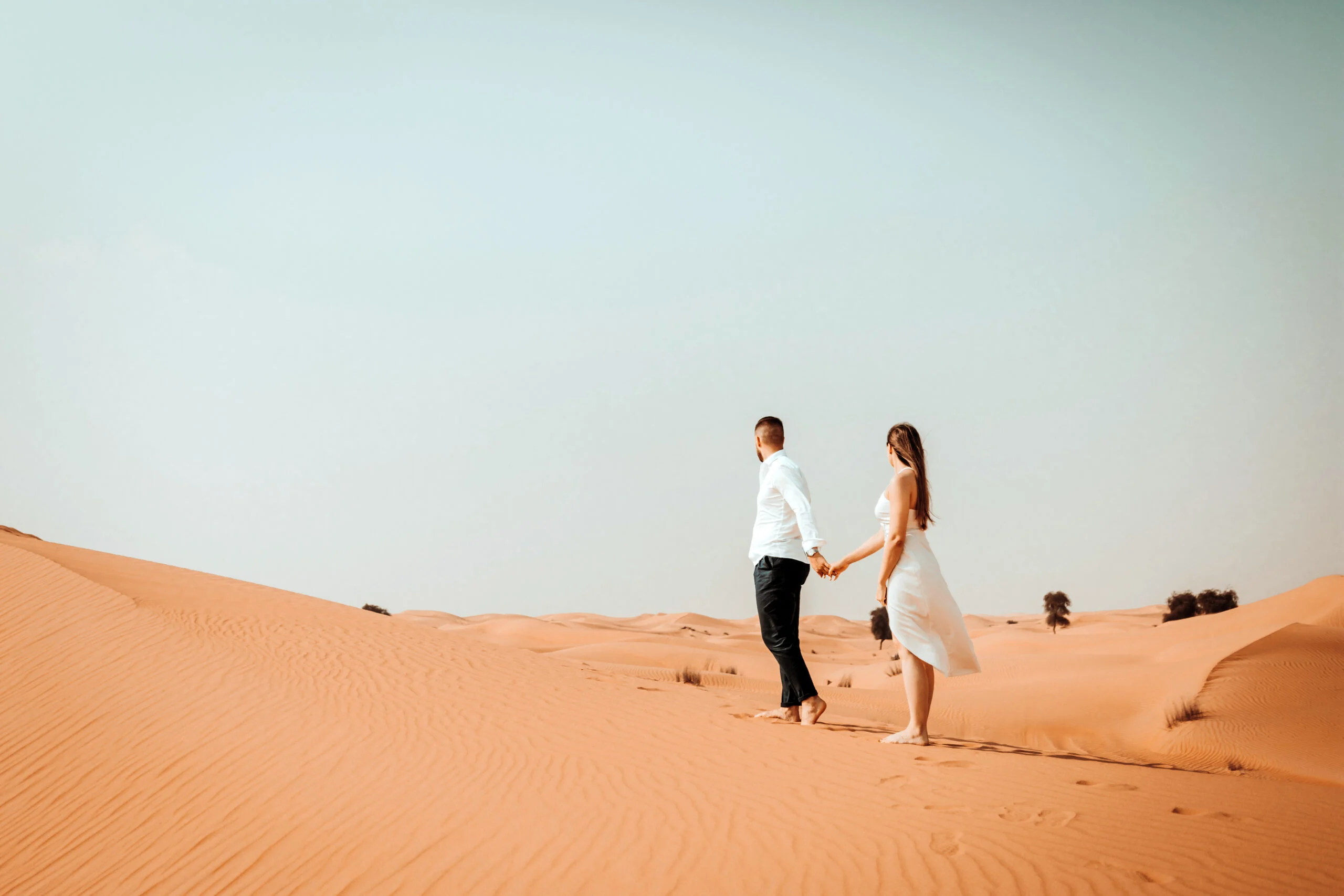 Couple walking hand in hand across the sand