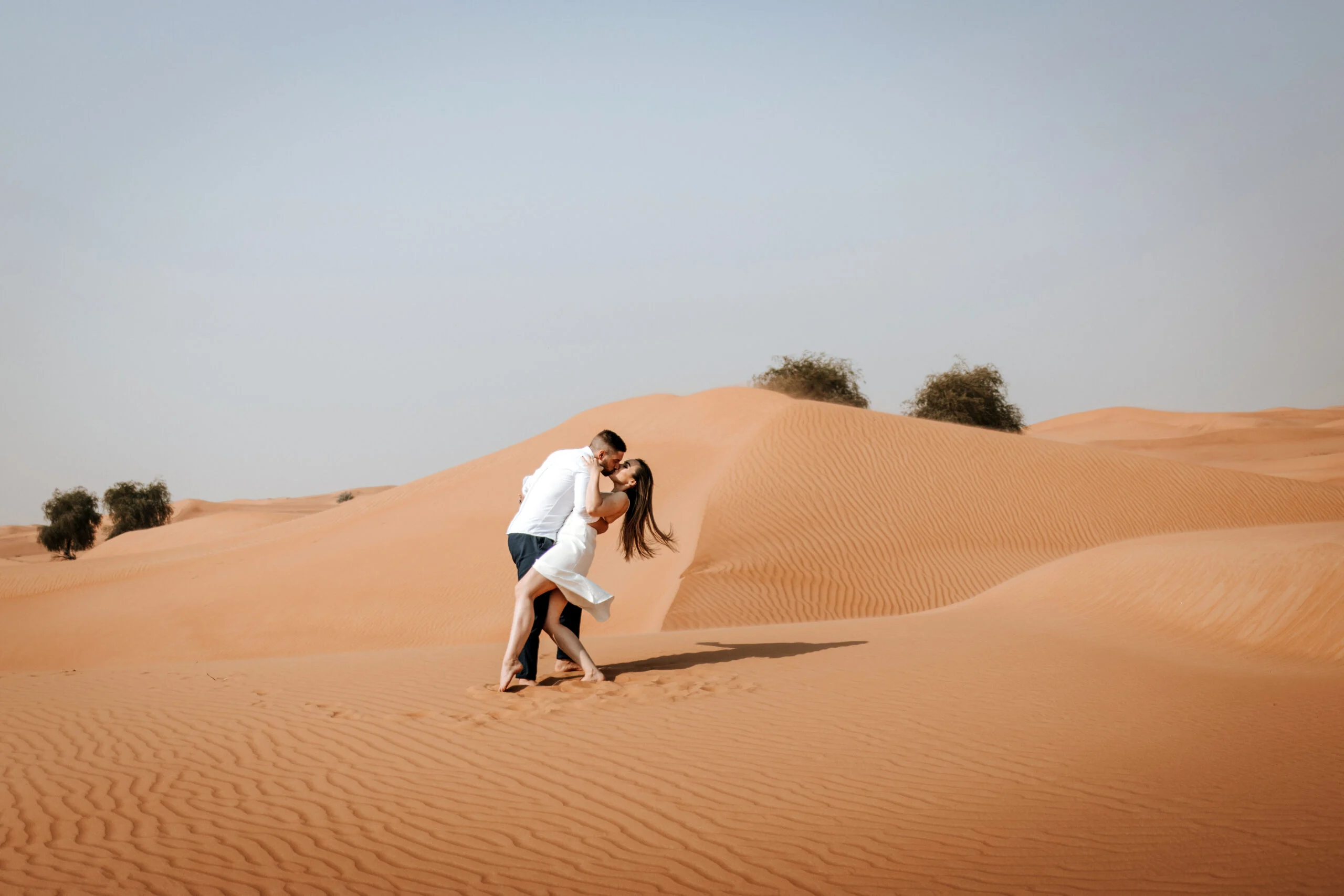 Couple running down the slope of a dune