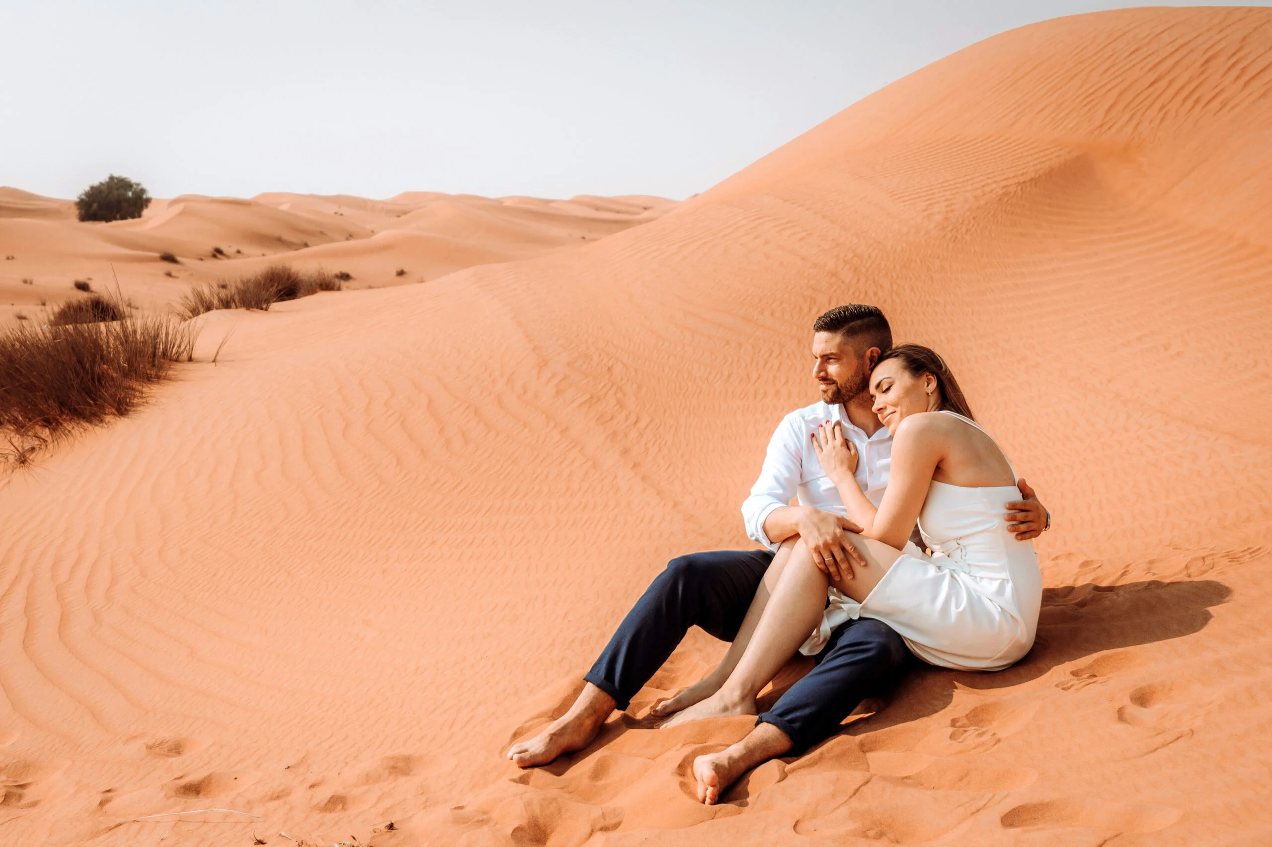 Couple sitting on the sand, laughing