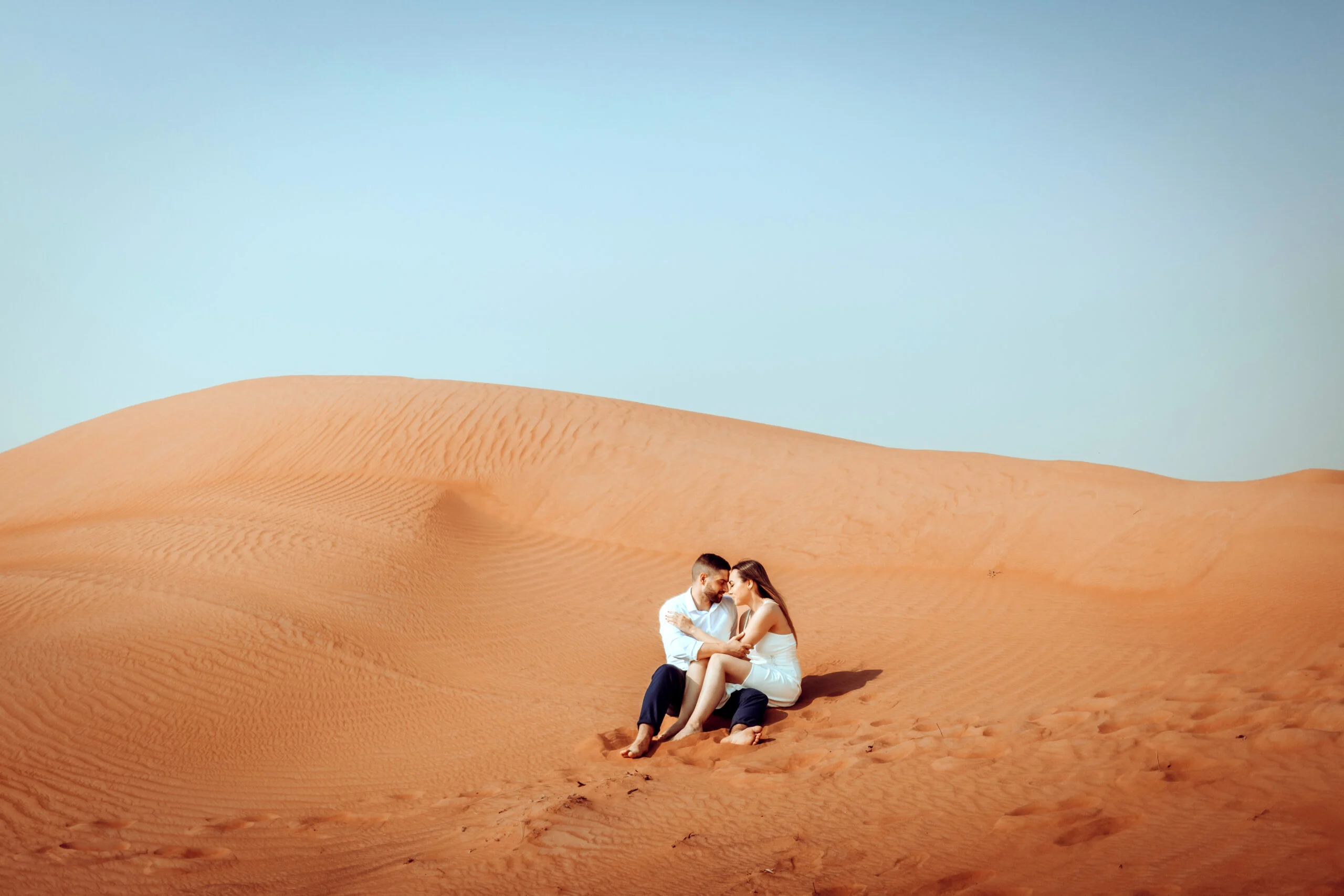 Couple sitting in the middle of the dunes seen from a distance