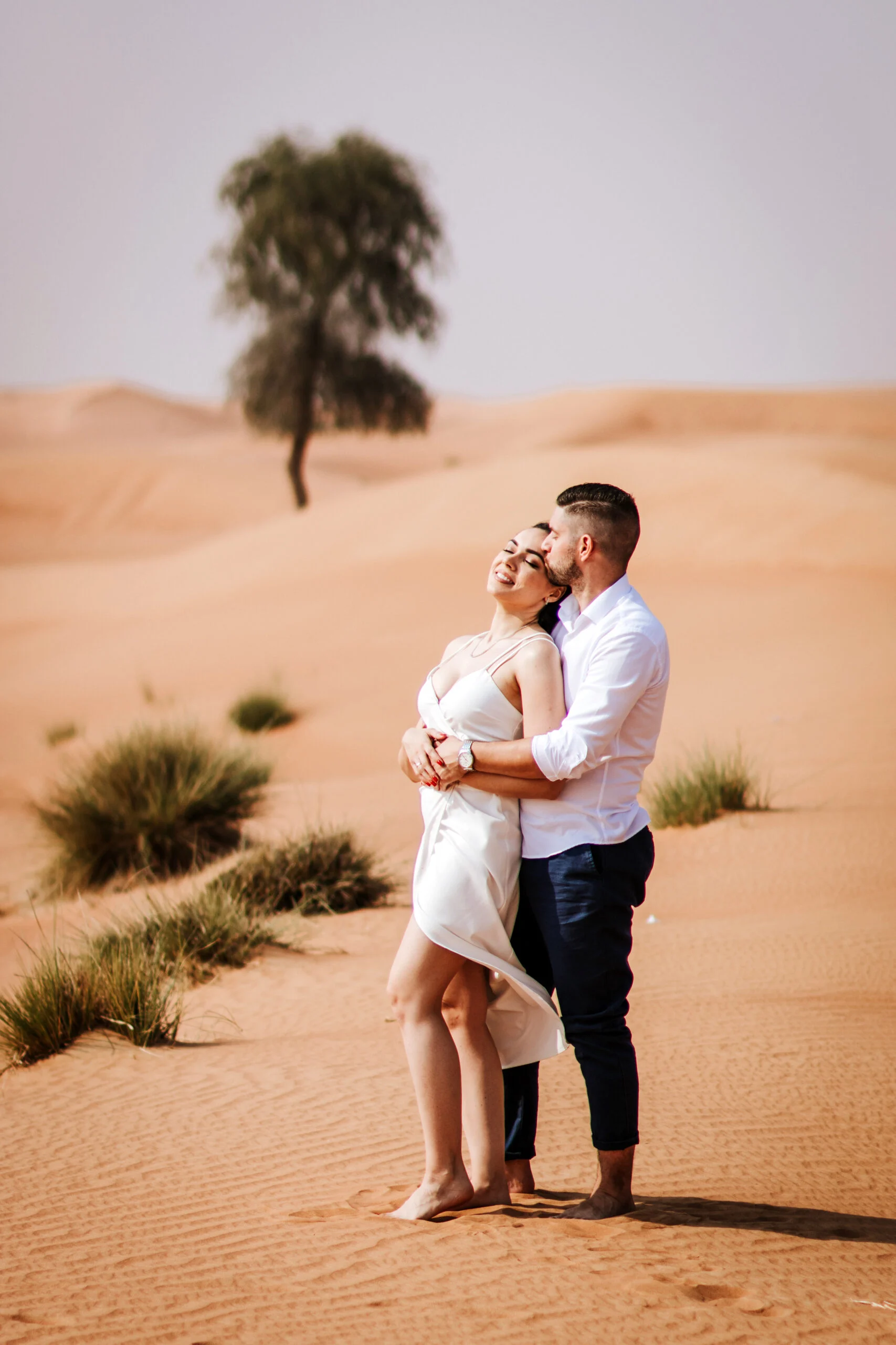 Couple embracing beside a lone desert tree