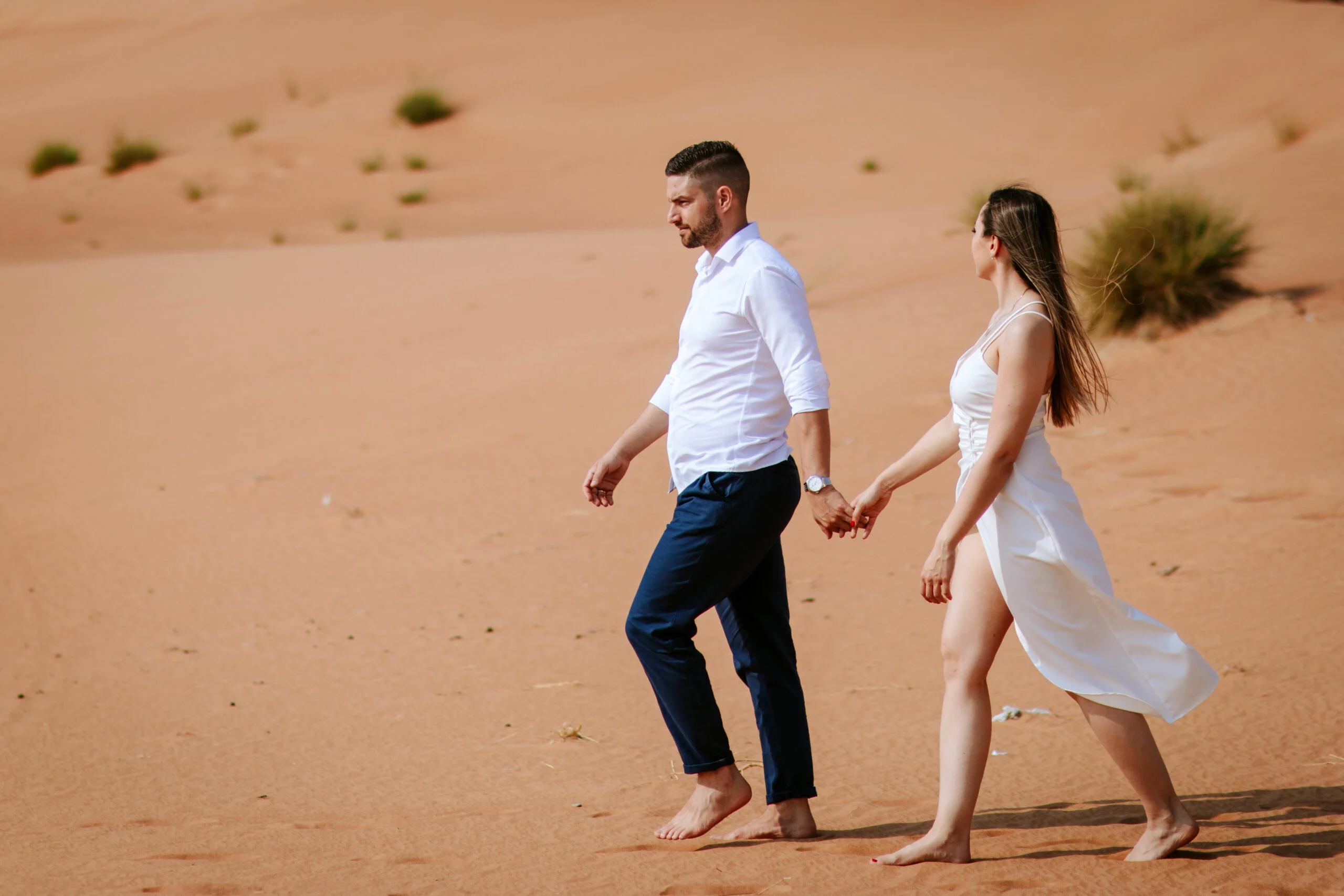 Couple walking hand in hand across the desert