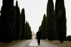 Bride and groom on the cypress road seen from a distance