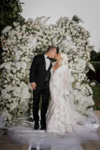 Bride and groom kissing under the white floral arch