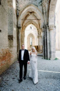 Bride and groom walking through the arcade of the ruined abbey