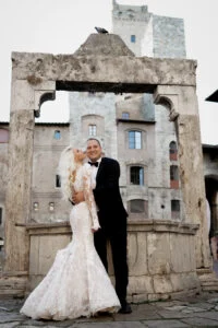 Bride and groom framed by a medieval stone arch