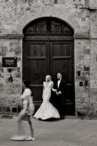 Bride and groom in a doorway as a passer-by crosses the frame