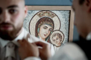 Groom being dressed in front of an Orthodox icon