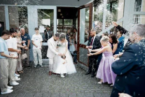 Guests throwing rice over the couple as they leave the church