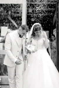 Black and white photograph of the bride and groom under falling rice