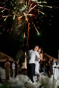 Couple embracing while fireworks light the sky above the celebration