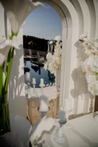 Detail of white flowers framing a view through an arched opening towards the water