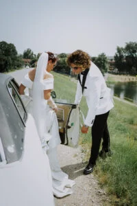 Groom holding the door of a vintage car open for the bride