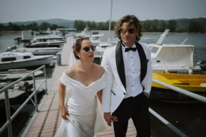 Bride and groom walking along a river marina lined with moored boats
